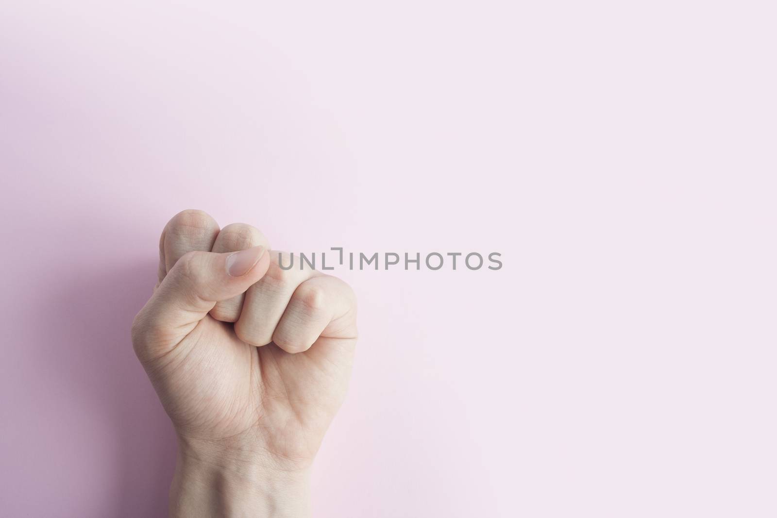 Man's hand with closed fist, on pink background. Copy space Close up. Males hand with a clenched fist 