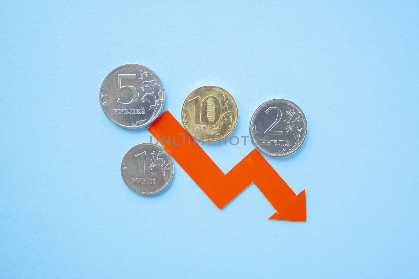 many rouble coins on blue background with red arrow down. exchange rate chart. ruble depreciation. Exchange rate of rouble fall. Rouble to dollar