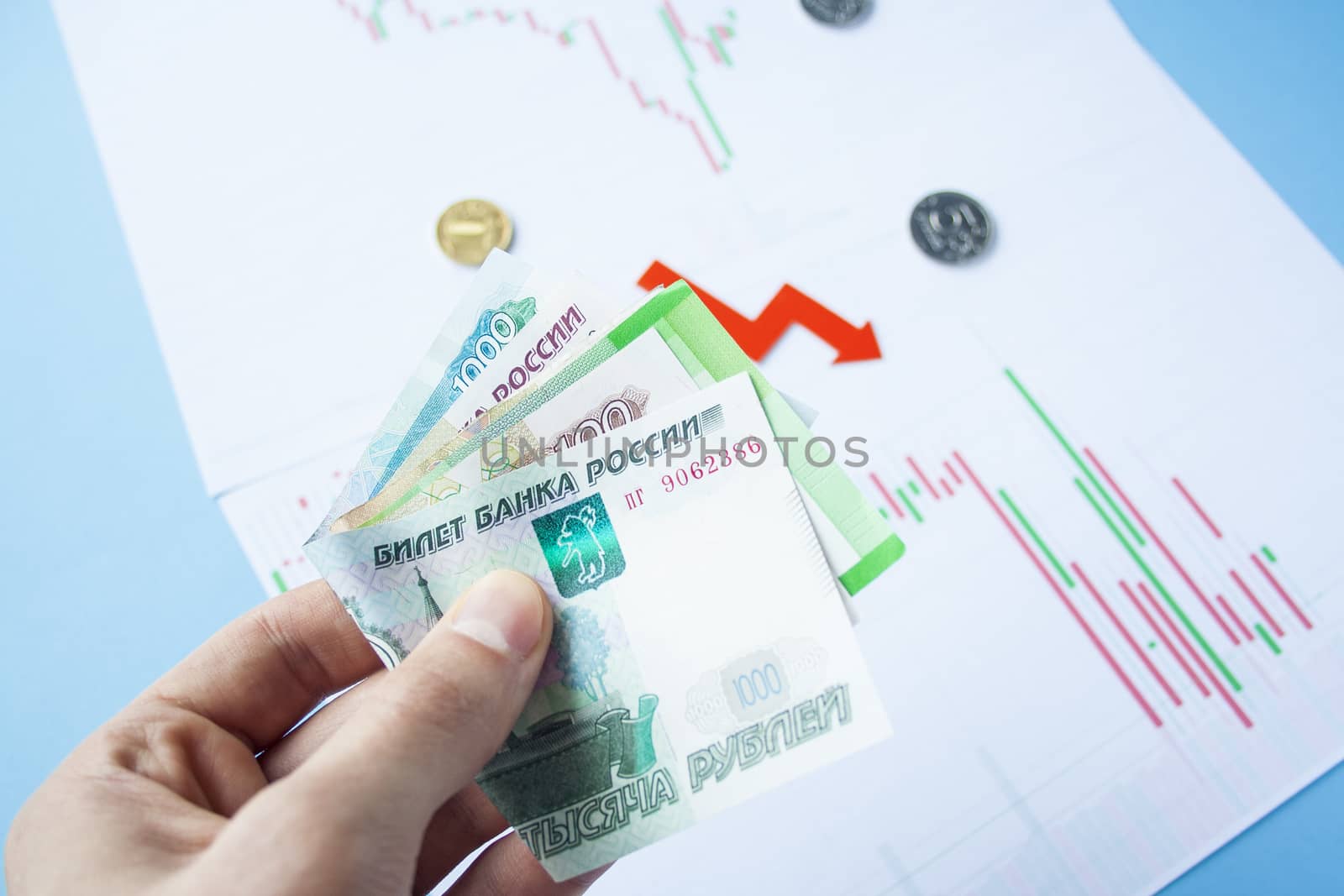 Male hand holding rouble bills on exchange rate of russian ruble and red arrow. ruble depreciation. Exchange rate of rouble fall. Rouble to dollar