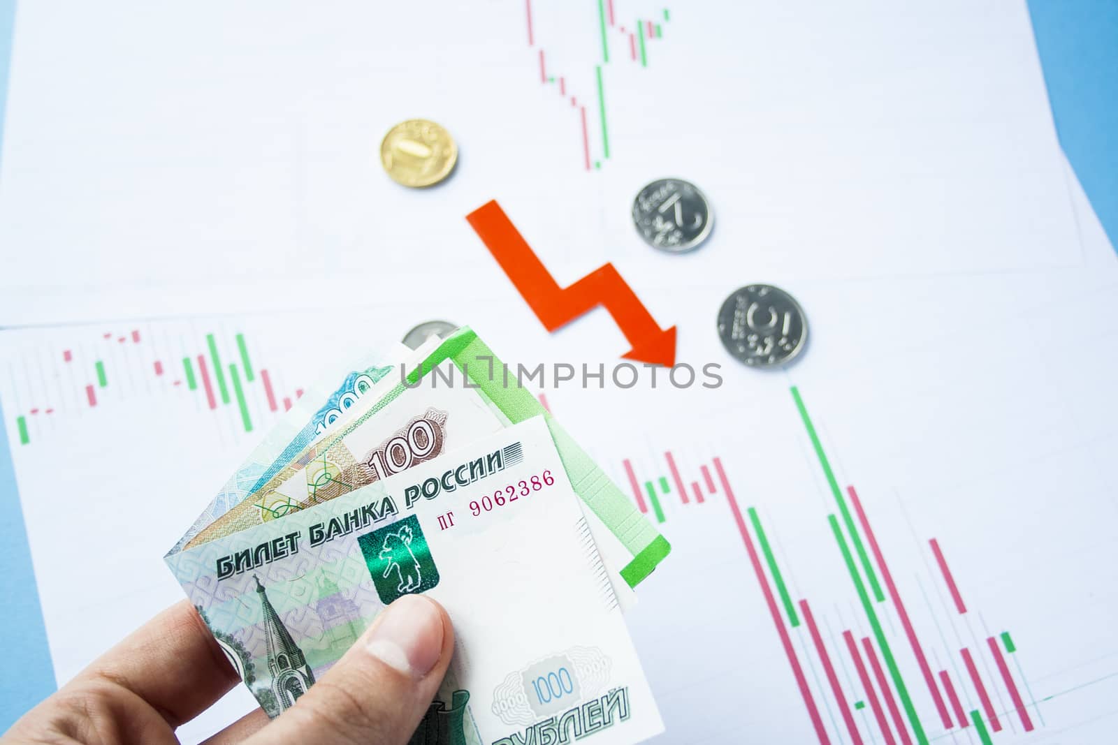 Male hand holding rouble bills on exchange rate of russian ruble and red arrow. ruble depreciation. Exchange rate of rouble fall. Rouble to dollar