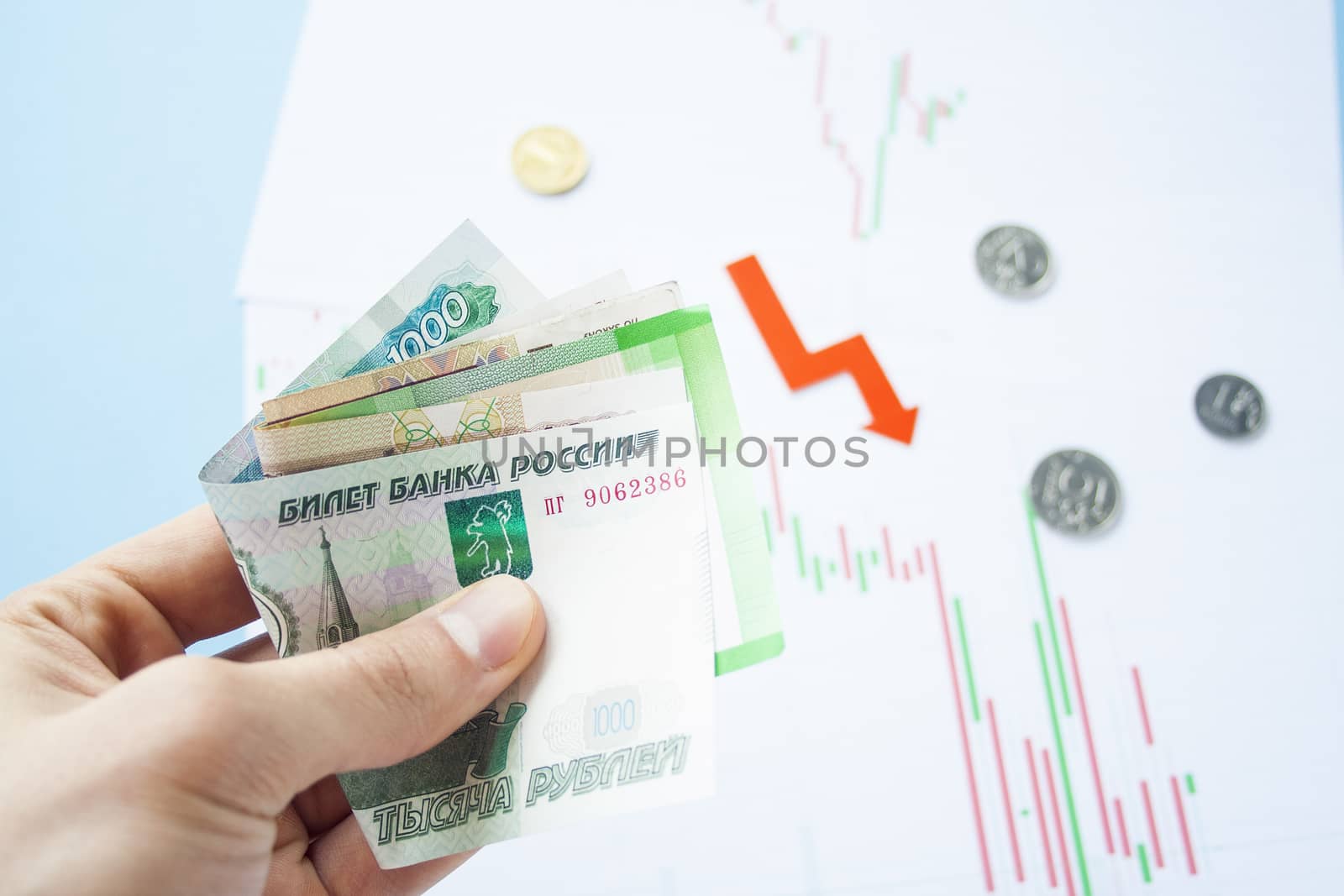 Male hand holding rouble bills on exchange rate of russian ruble and red arrow. ruble depreciation. Exchange rate of rouble fall. Rouble to dollar