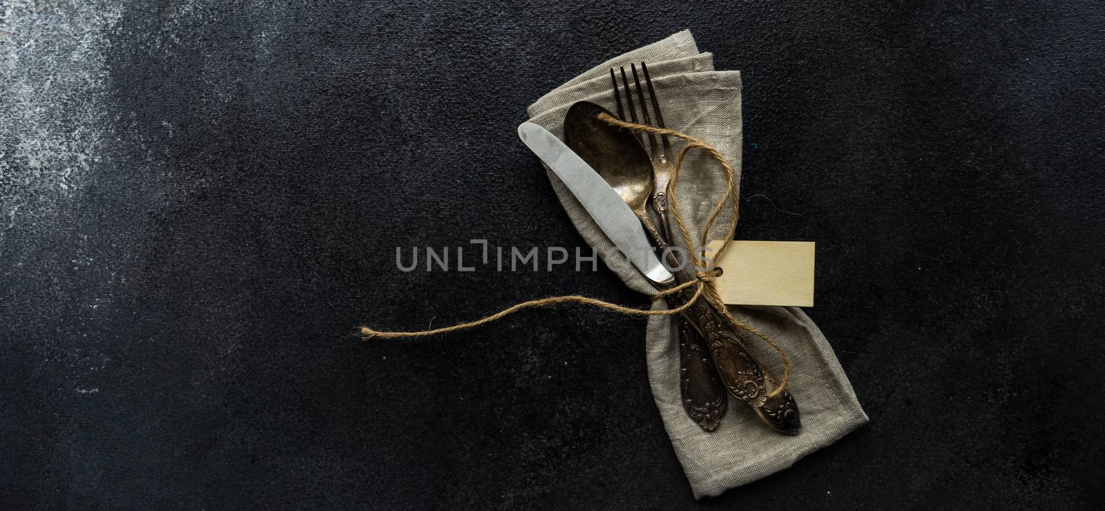 Table setting with cutlery and napkin on concrete background with copy space