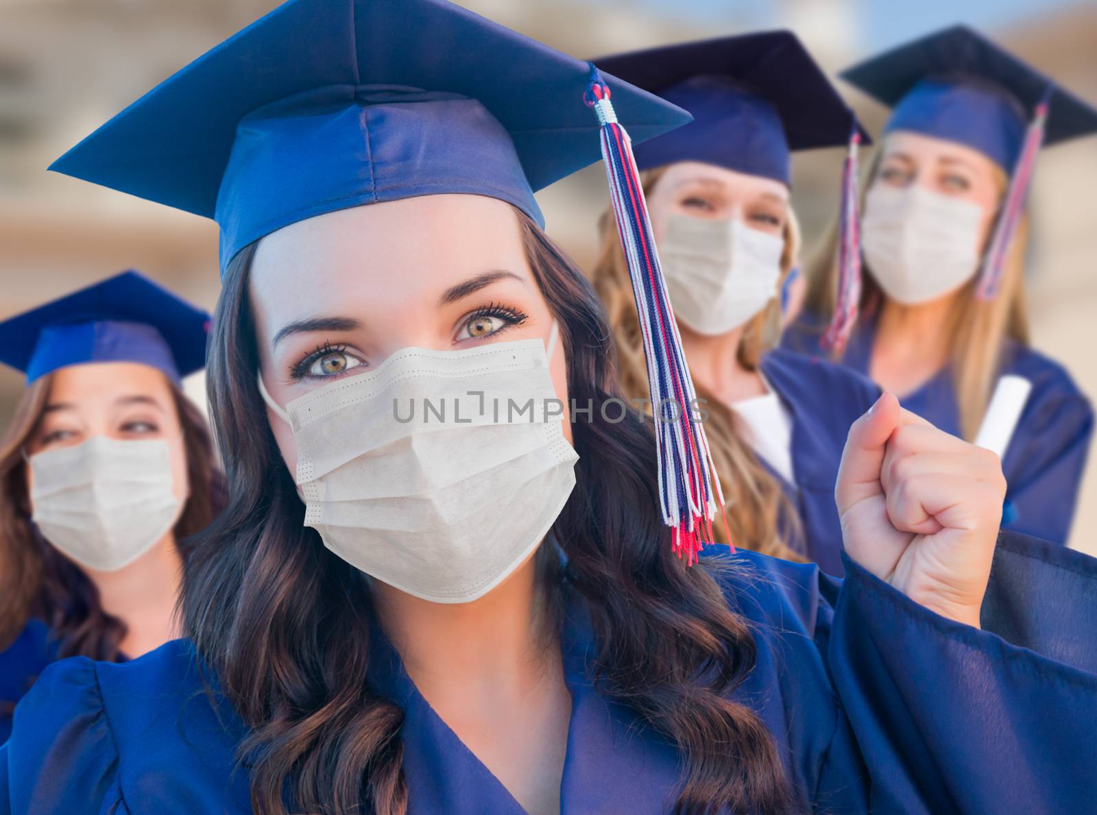 Several Female Graduates in Cap and Gown Wearing Medical Face Masks.