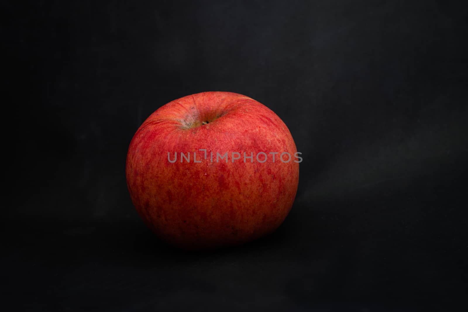 A fresh red apple with droplets of water against black background with space for text