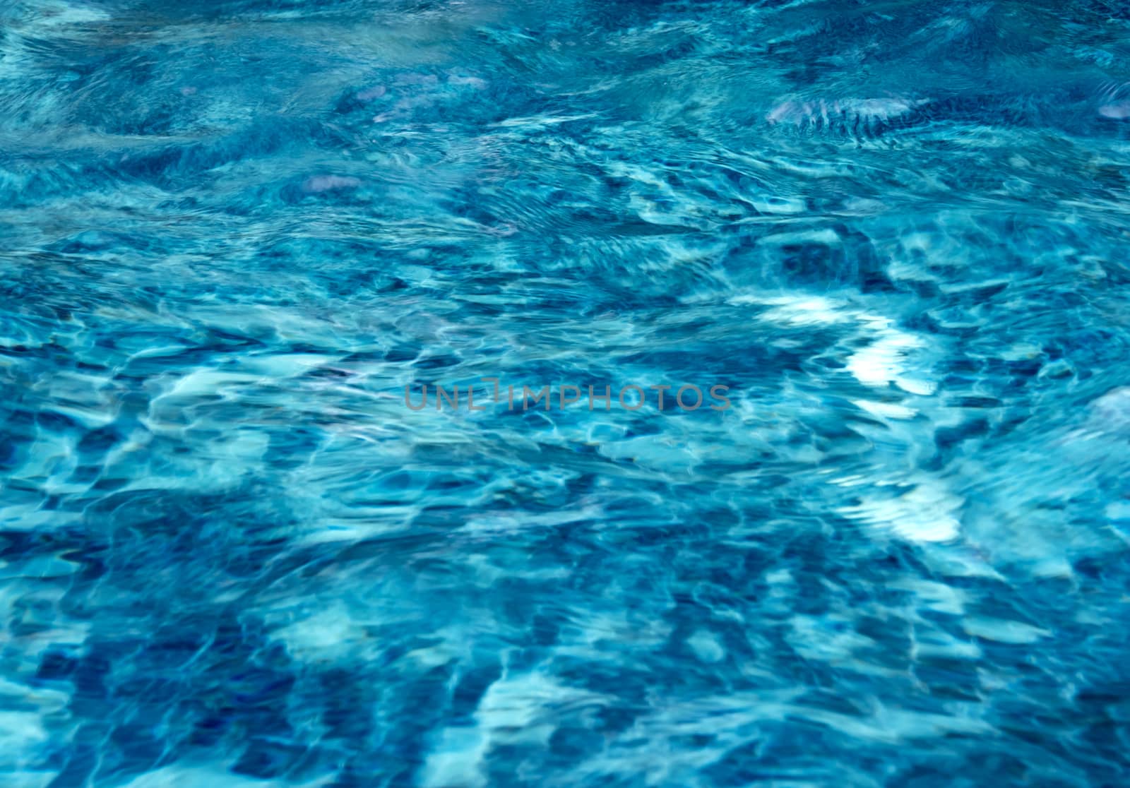 Reflection of sunlight and blue sky on the moving water surface in the pool