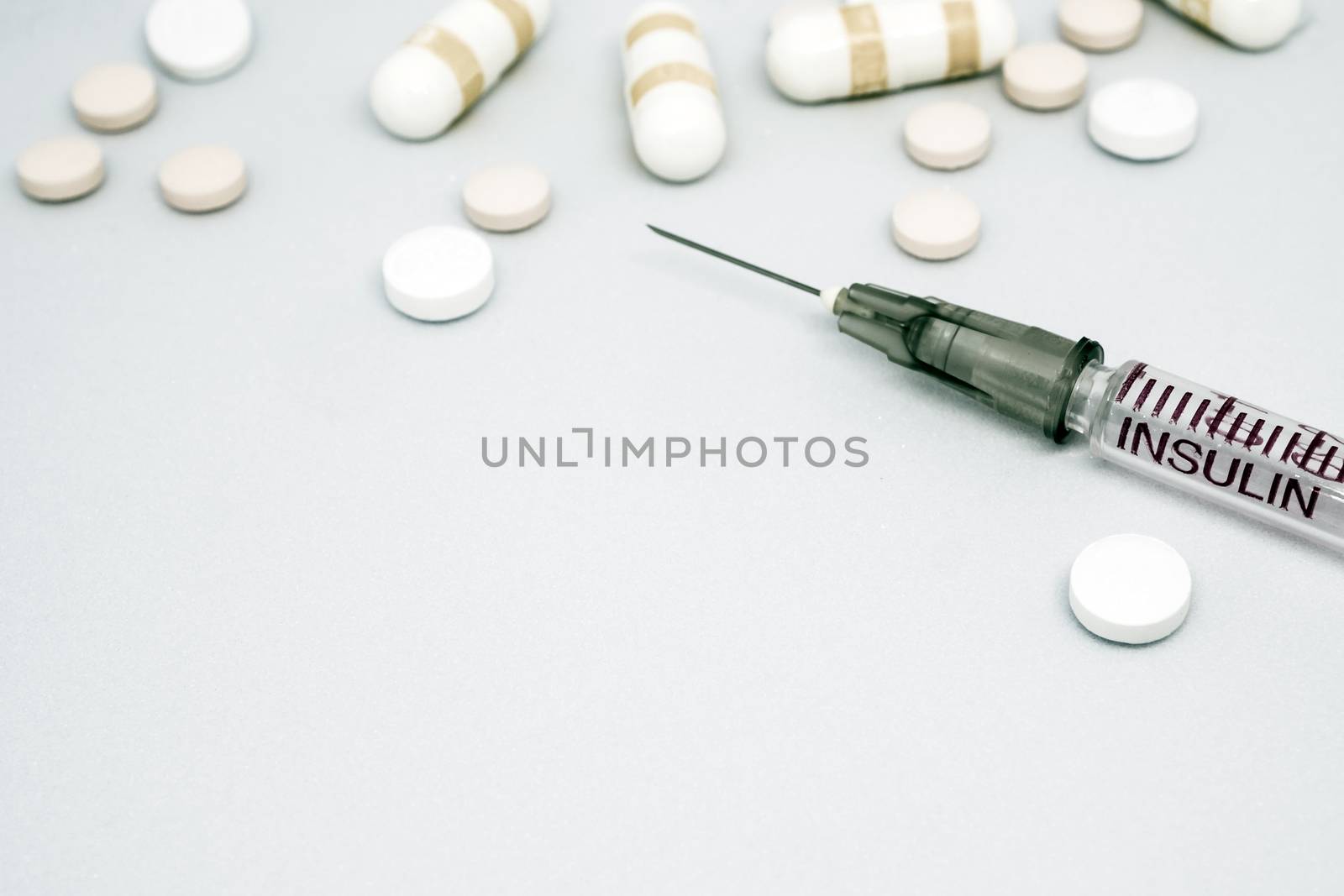 Insulin syringe, injection needle and some pill on white background