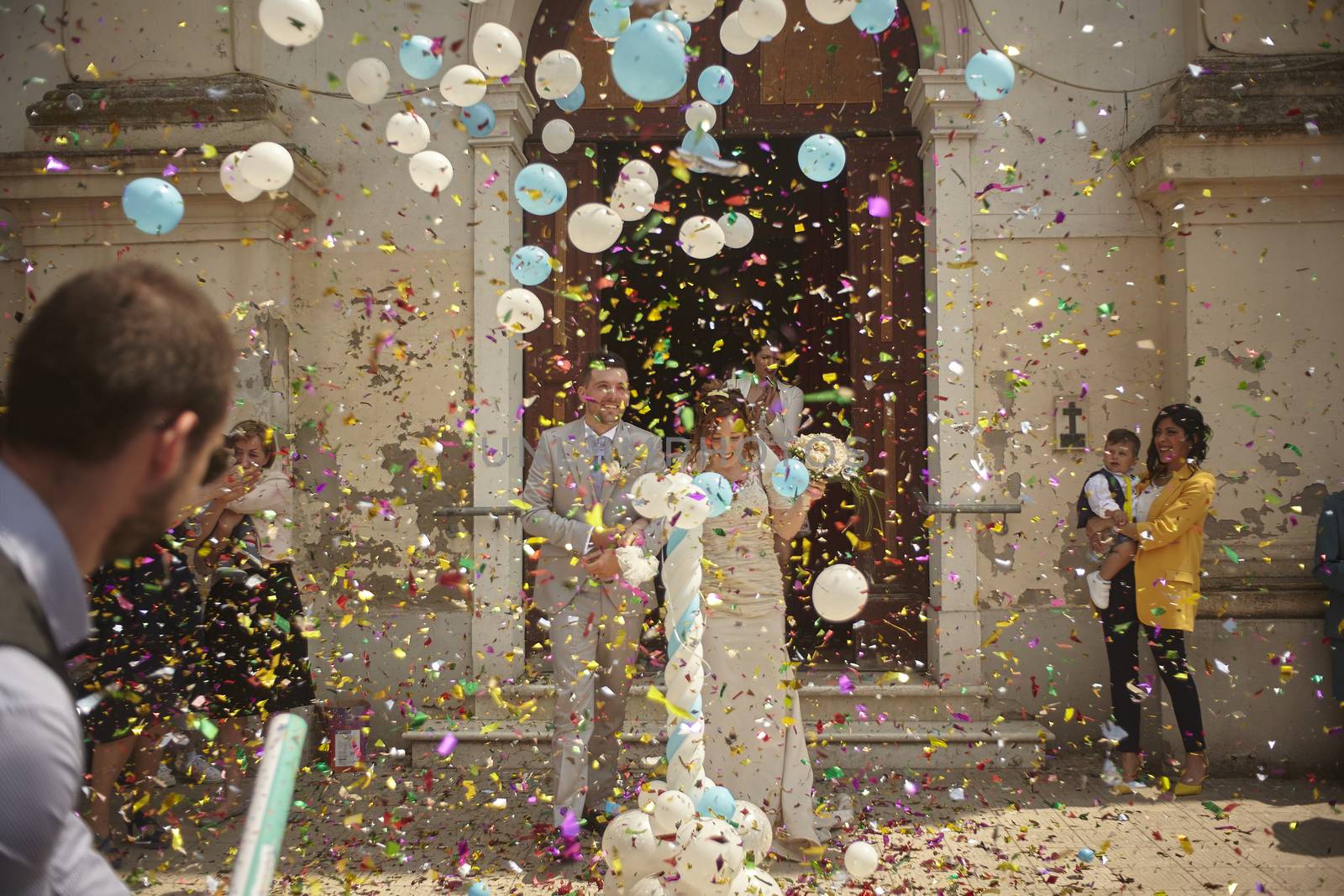 Newlyweds outside the church with confetti and rice throwing
