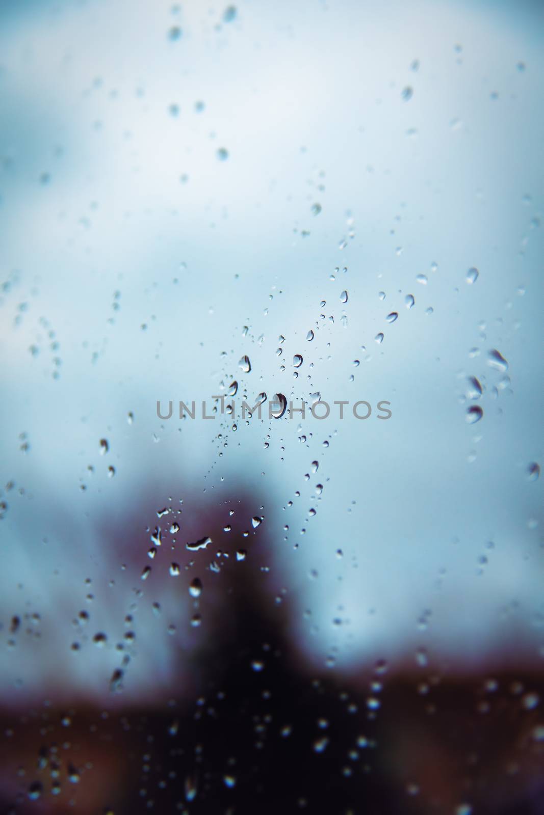 Rain drops on a window surface with blurry shadows by Mendelex