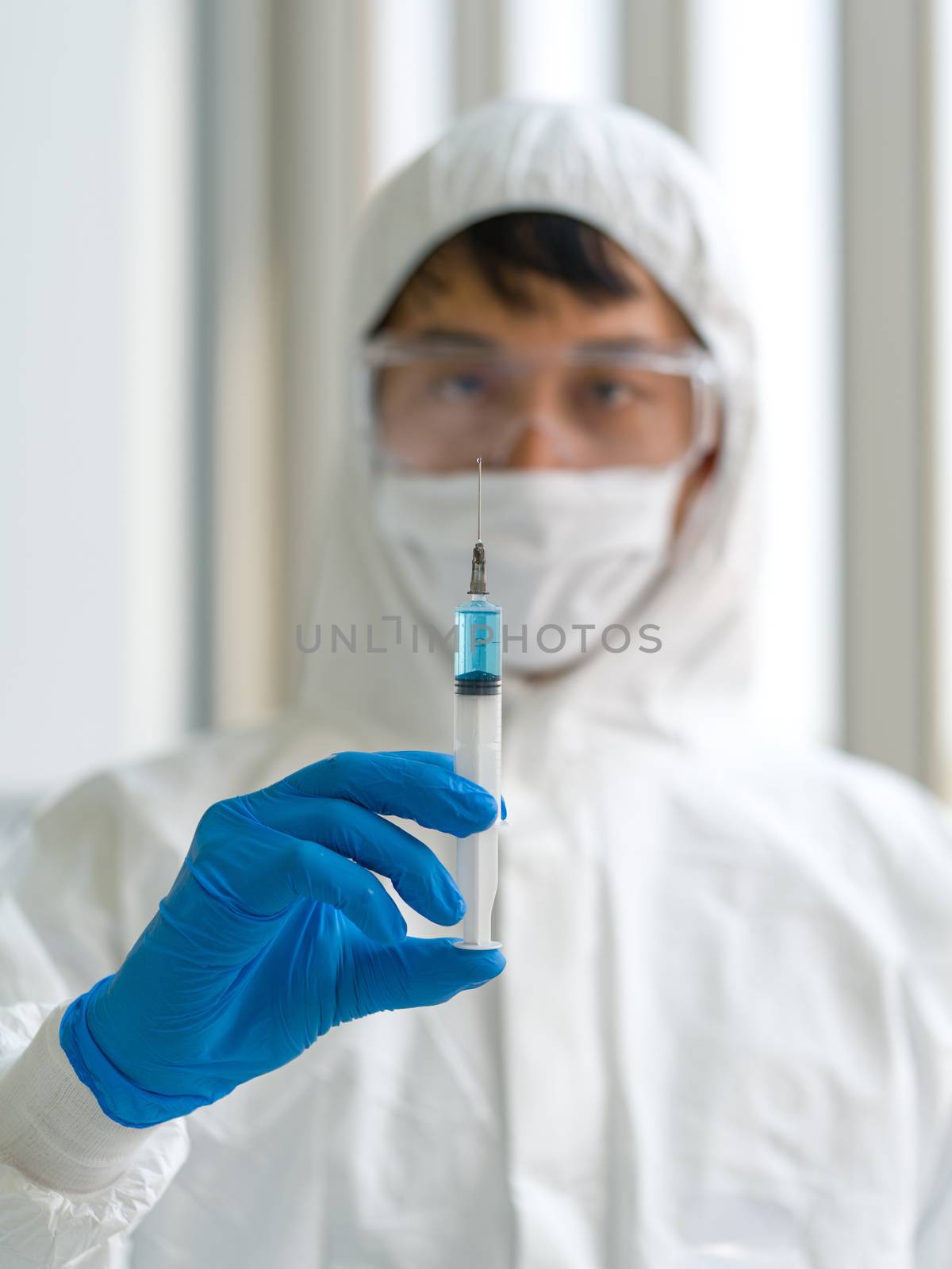 A syringe containing a blue anti-virus drug in the hands of researchers. Coronavirus disease 2019 testing process in a laboratory.