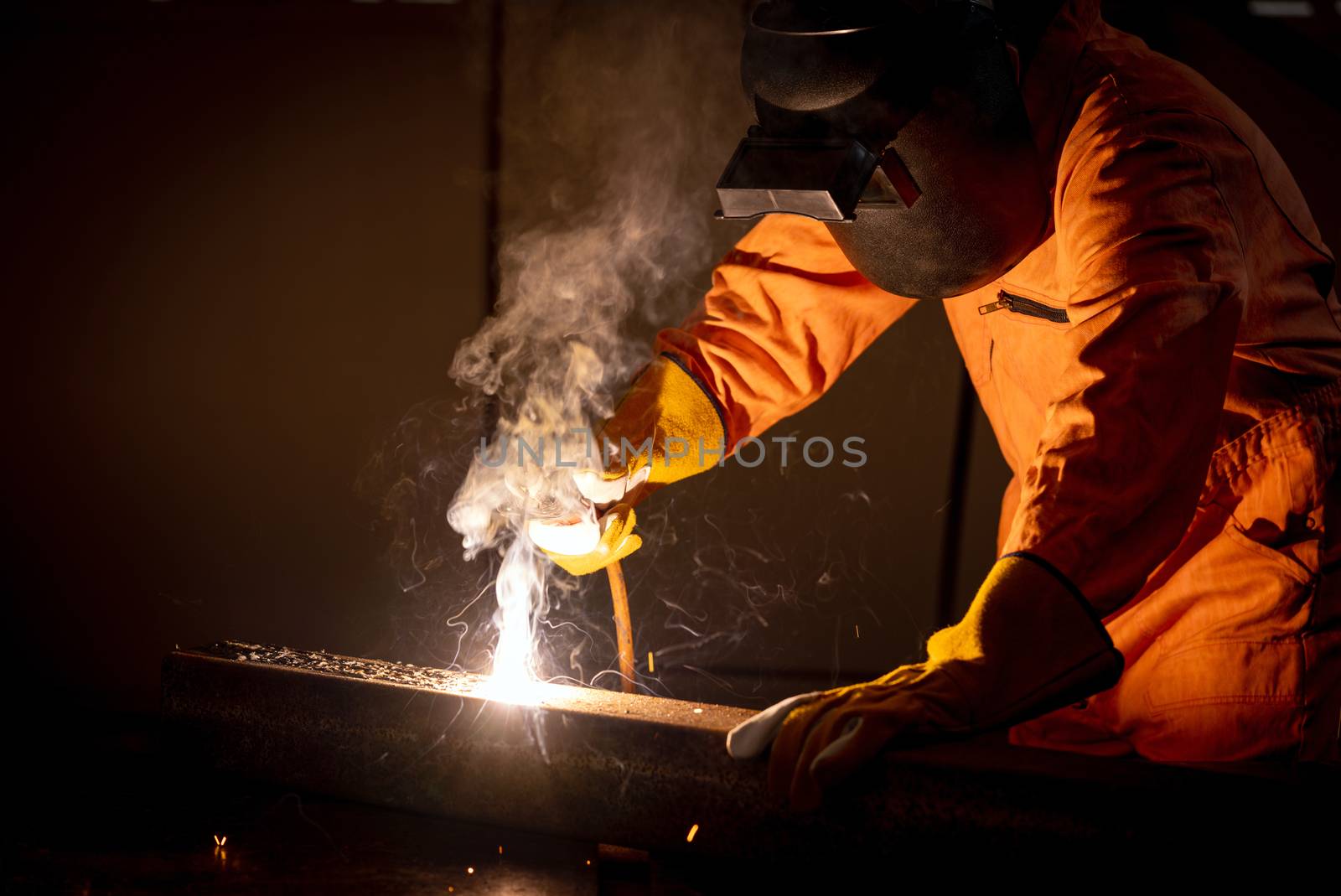 Metal industry workers are welding steel sheets for real estate projects received. Sparkler on dark background, close-up. Heavy work in factory.