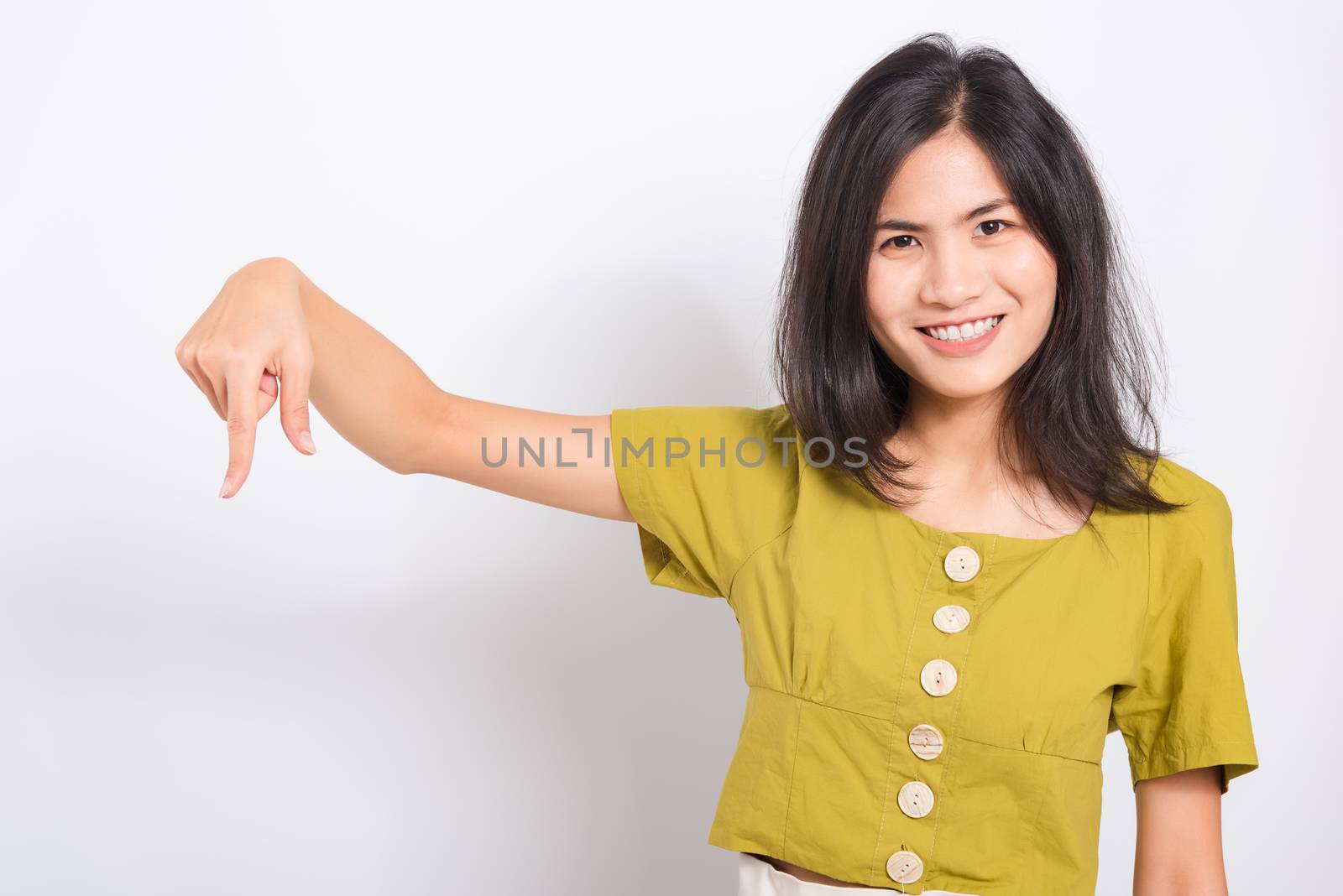 Portrait Asian beautiful young woman standing, She points down to space with fingers and looking to camera, shoot photo in a studio on white background, There was copyspace