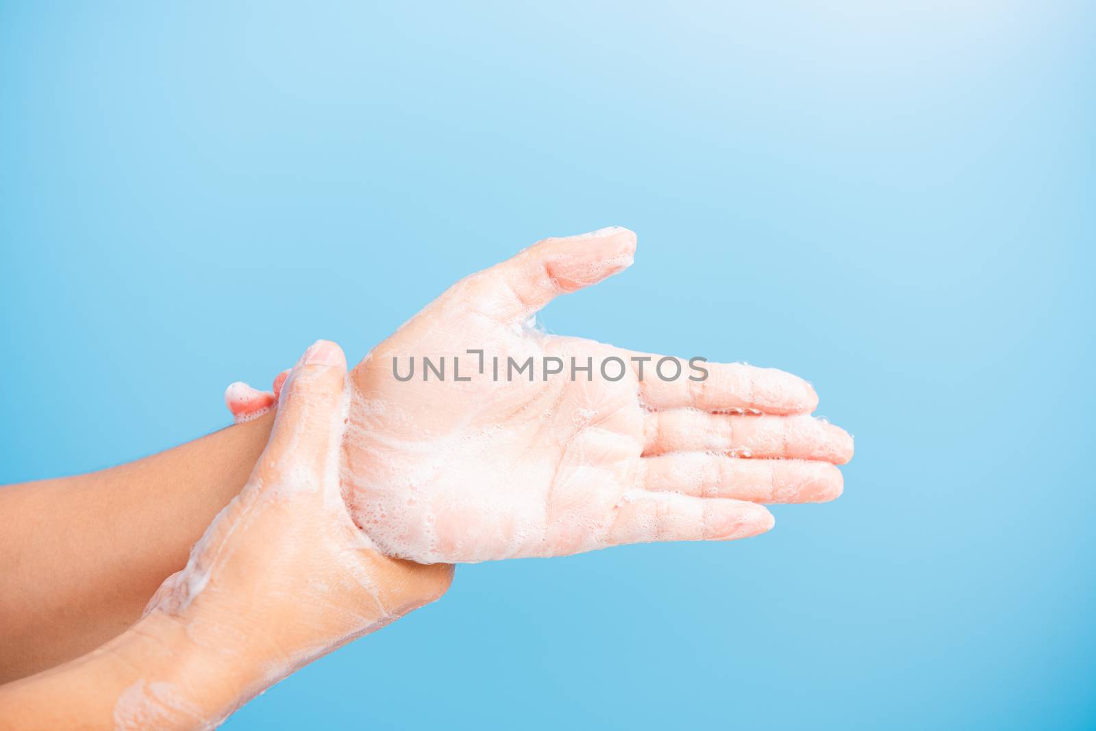 Closeup body care Asian young woman washing hands with soap have foam, hygiene prevention COVID-19 or coronavirus protection concept, isolated on blue background