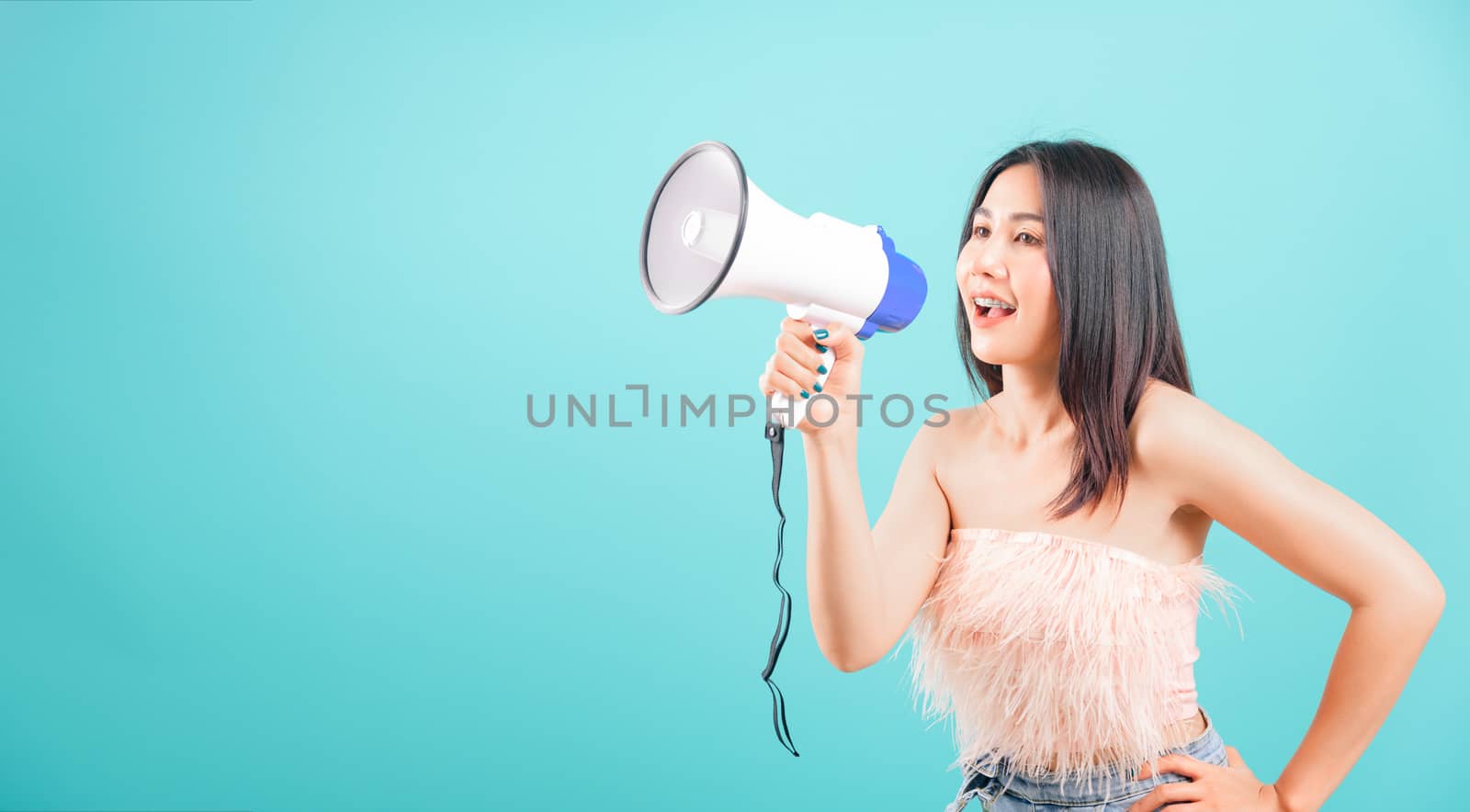 Smiling face portrait asian beautiful woman her usring megaphone on blue background, with copy space for text