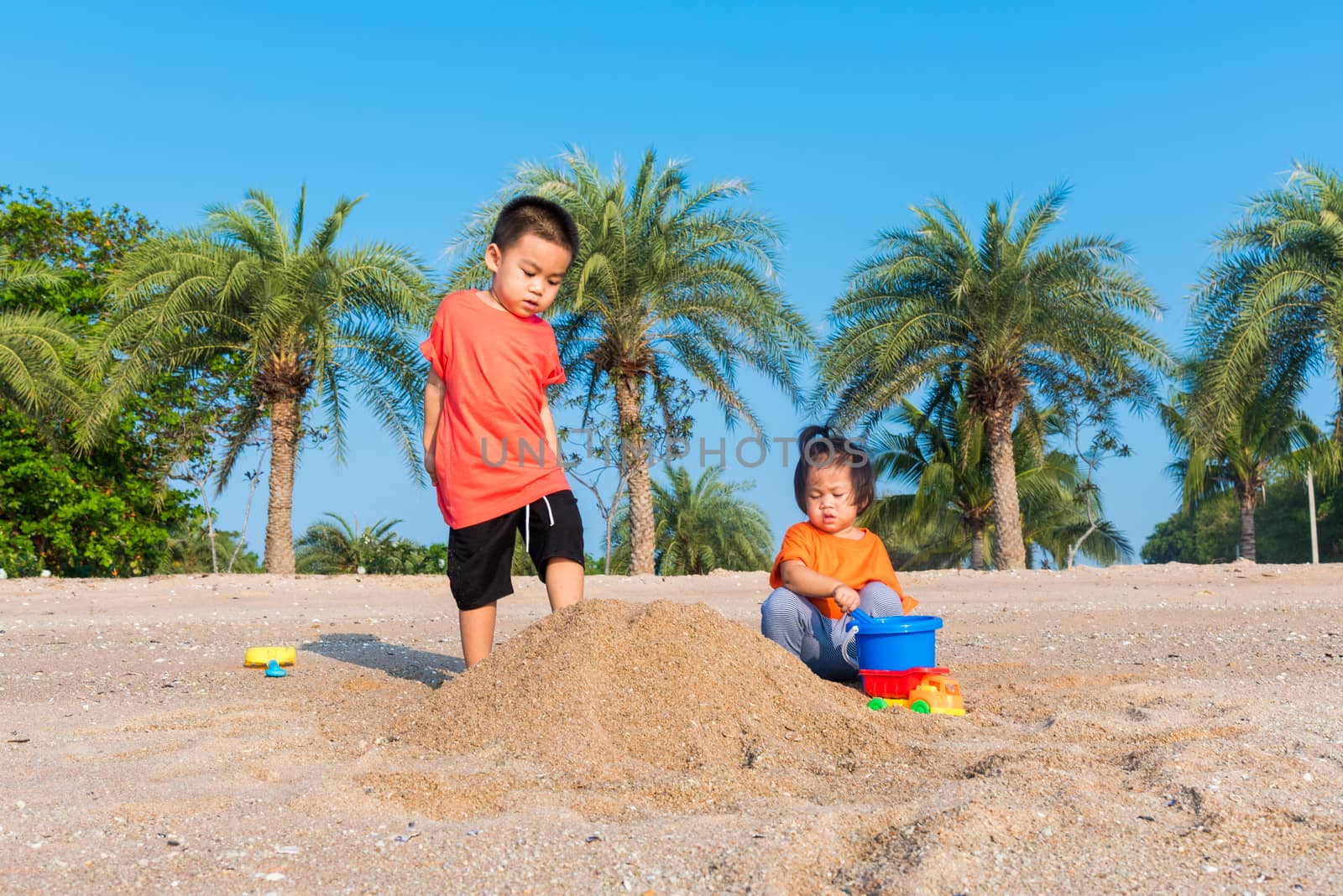 Brother and sister two children funny digging play toy with sand by Sorapop