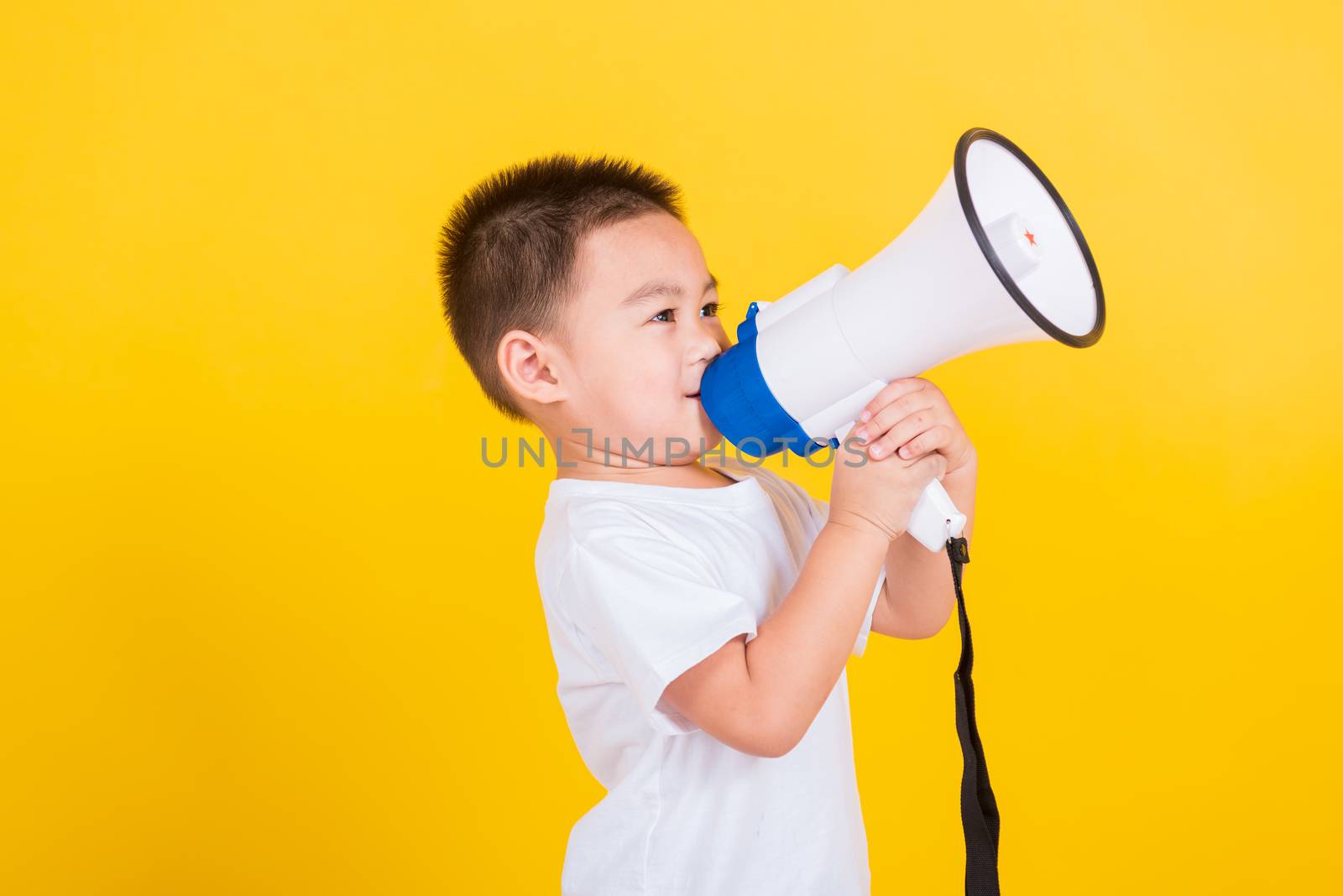 child boy holding and shouting or screaming through the megaphon by Sorapop