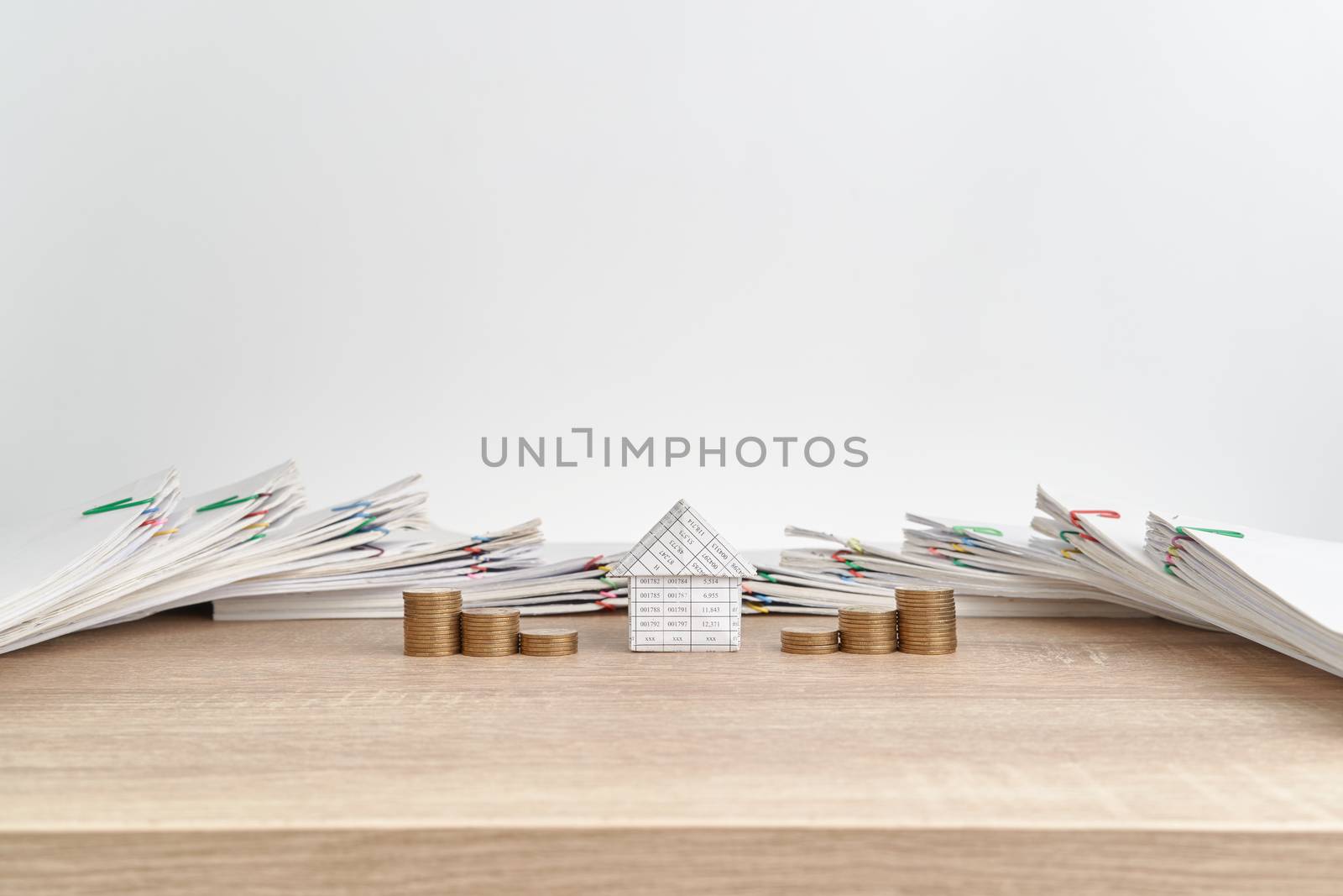 House between step pile of gold coins on wooden table have pile of paperwork of report of sale and receipt as background and copy space. Business and finance concepts rich and successful photography.