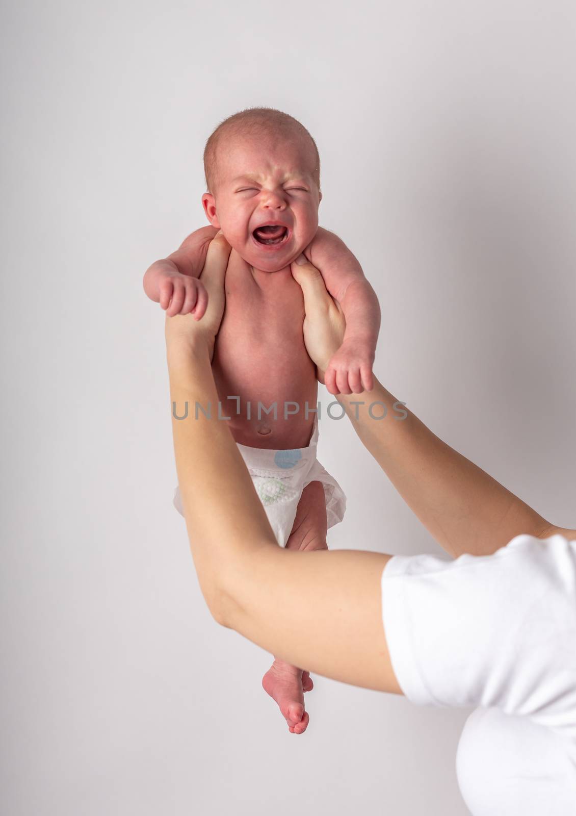 Portrait of a screaming newborn hold at hands, family, healthy birth concept photo, close up.