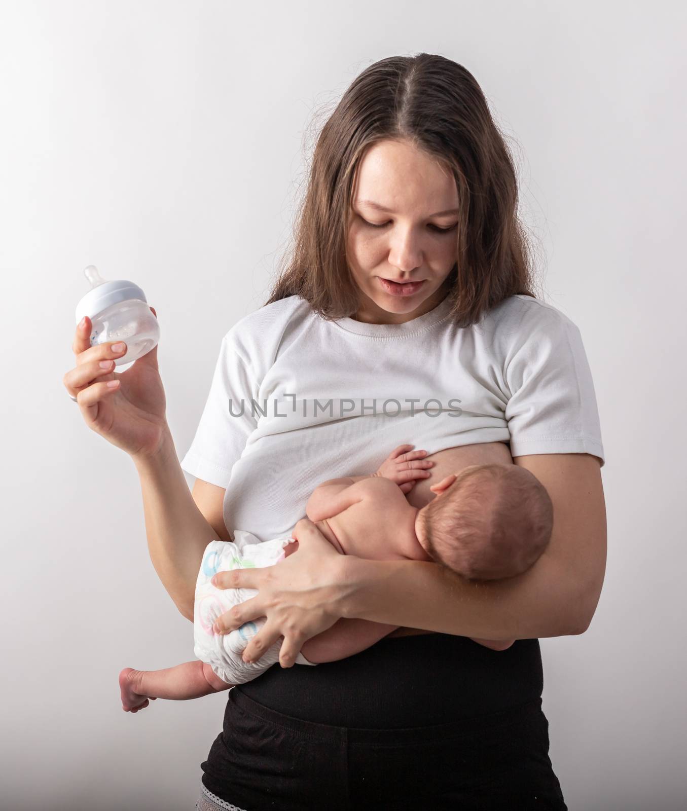 A mother breastfeeds a baby, not a bottle. Natural feeding concept