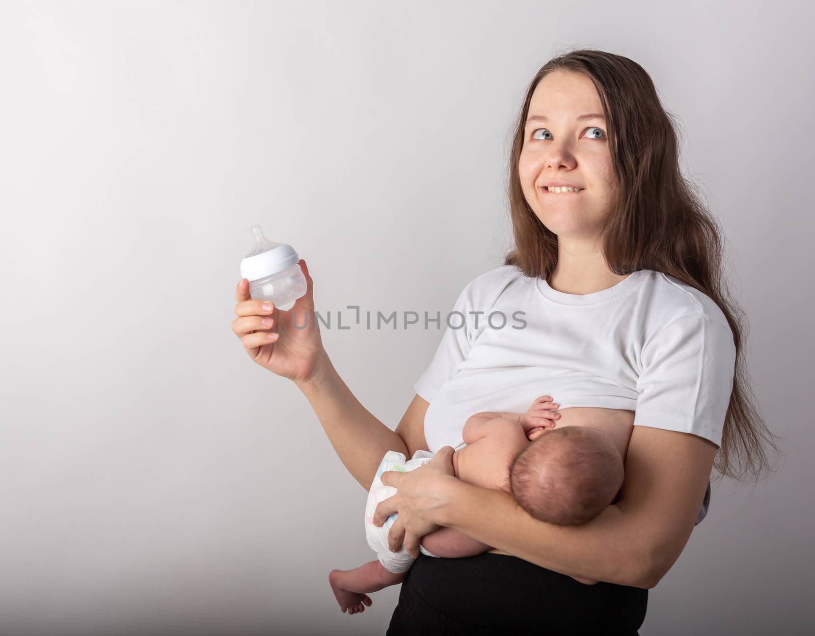 A mother breastfeeds a baby, not a bottle. Natural feeding concept