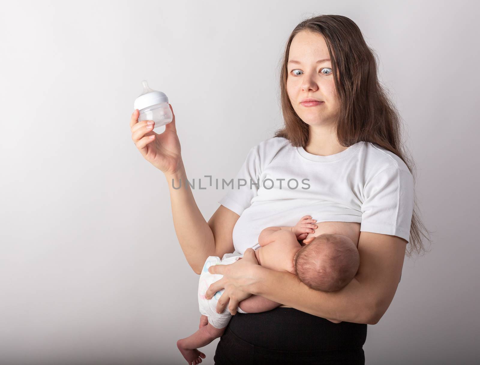 A mother breastfeeds a baby, not a bottle. Natural feeding concept