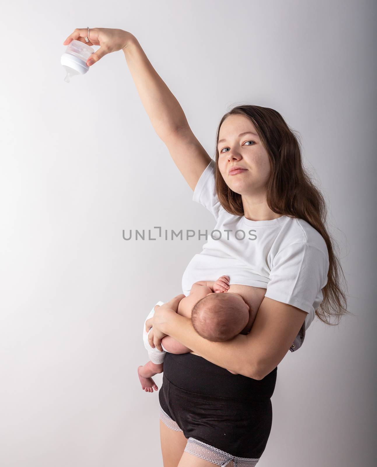 A mother breastfeeds a baby, not a bottle. Natural feeding concept. by Vassiliy