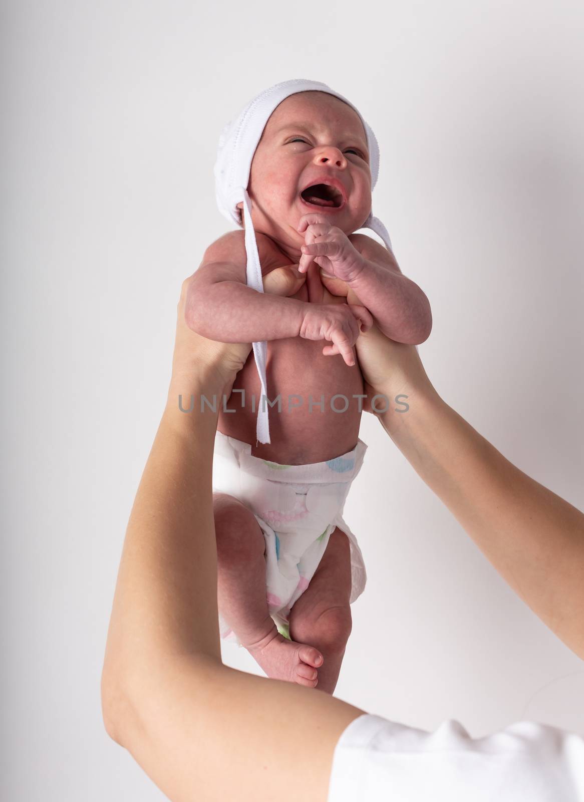 Portrait of a screaming newborn hold at hands, family, healthy birth concept photo, close up.