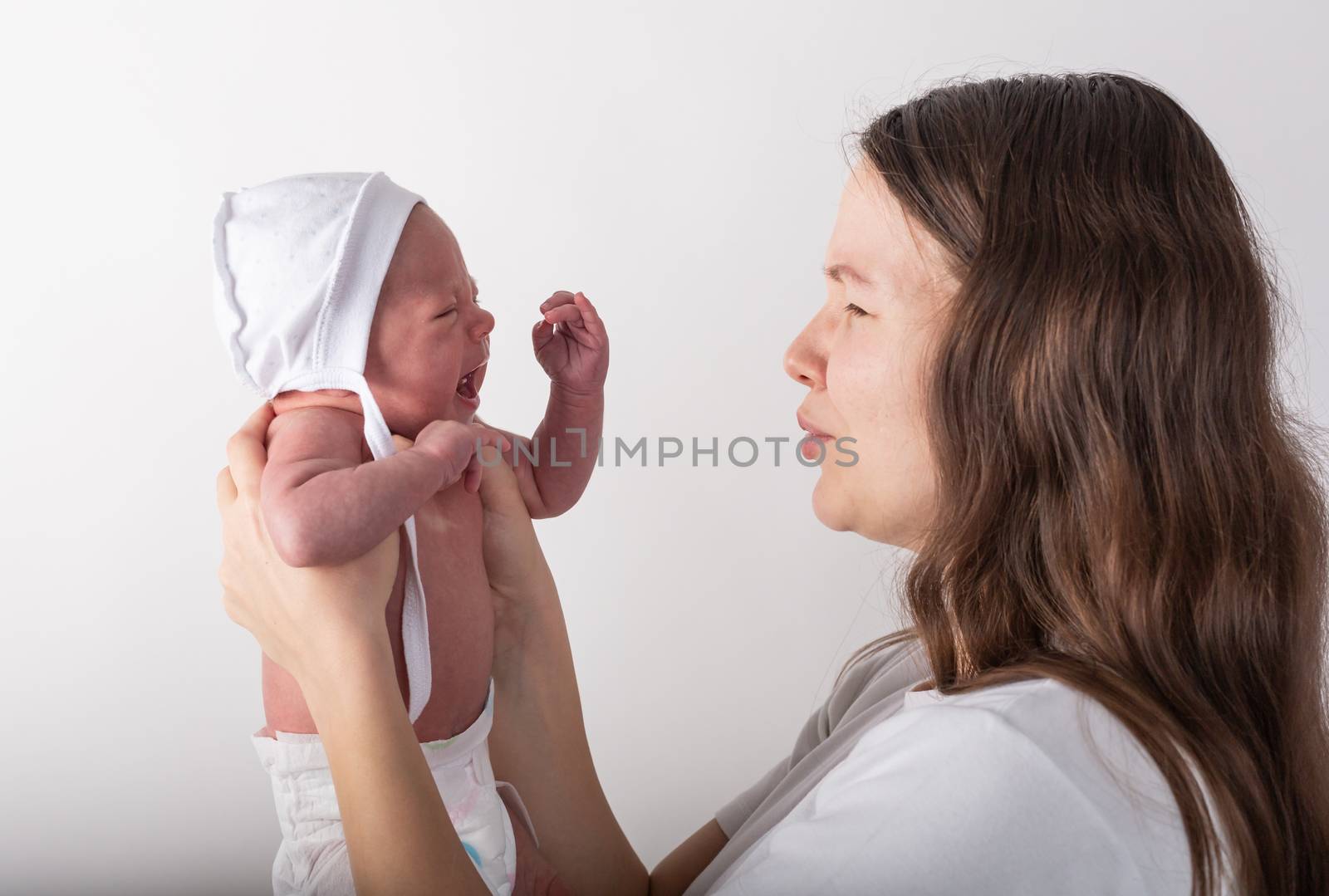 Newborn baby cries in the arms of his mother.