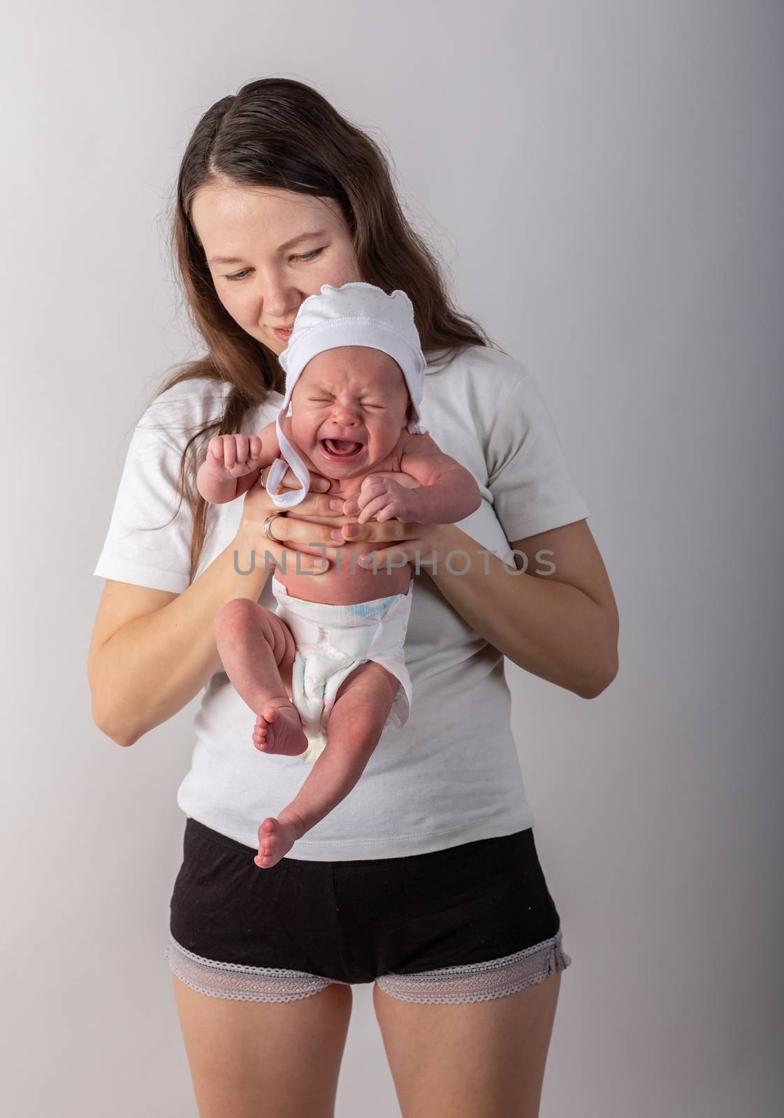 Newborn baby cries in the arms of his mother.