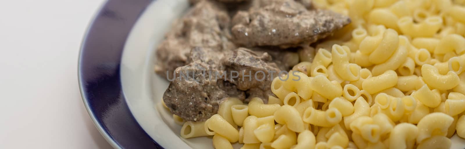 Chicken liver stewed in sour cream and a side dish of pasta in a bowl on a white background, close-up. healthy food, menu concept background