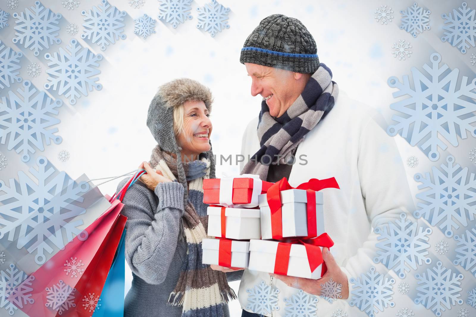 Mature couple in winter clothes holding gifts against snowflake frame