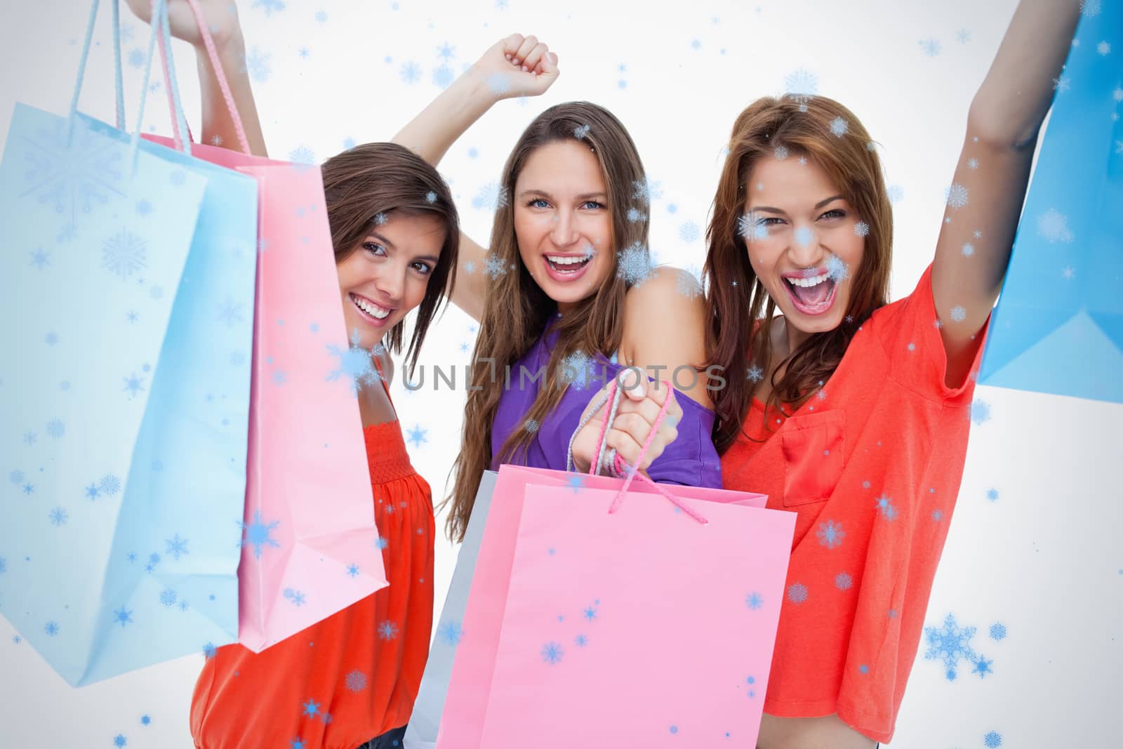 Young women elevating their purchase bags against snow falling