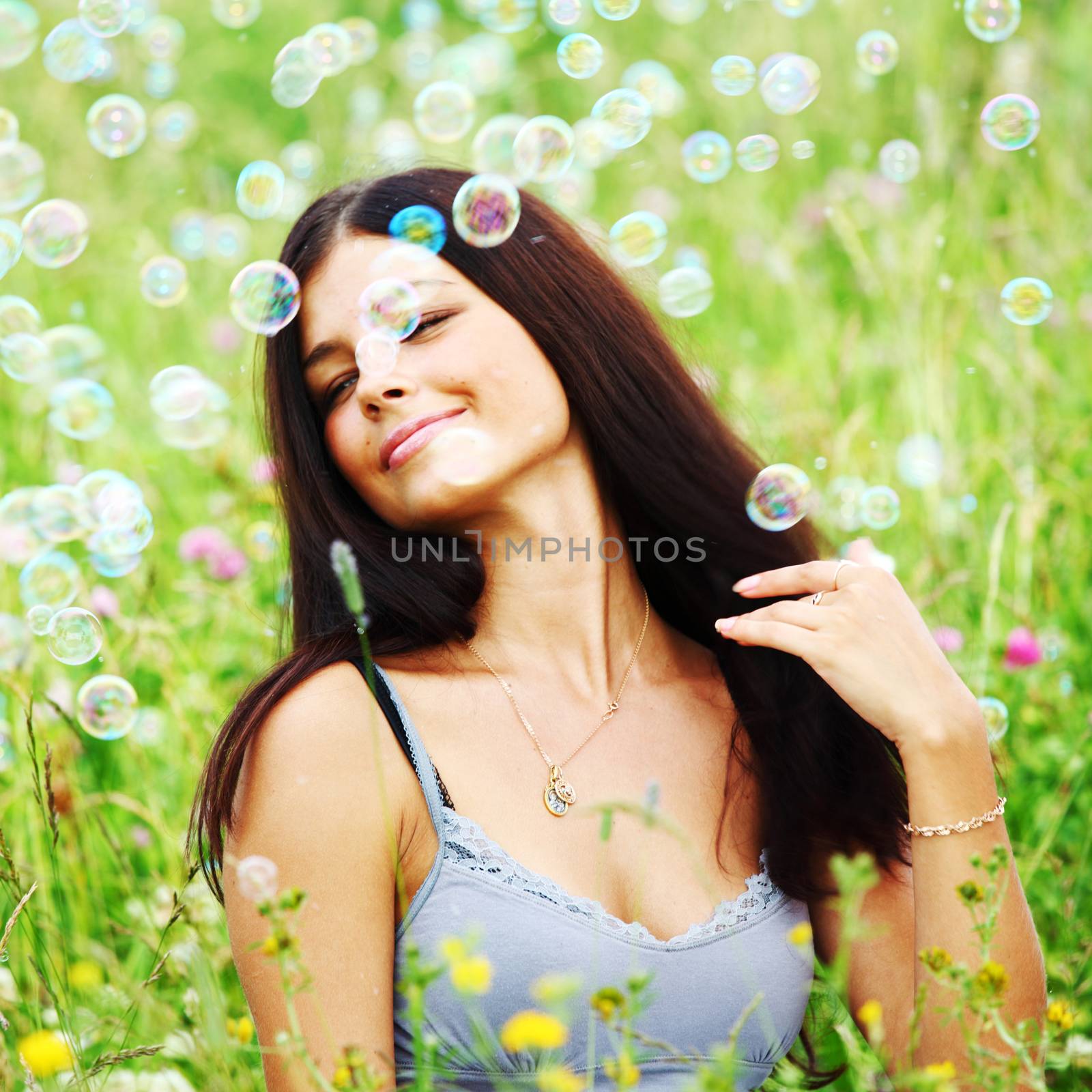 Happy woman smile in green grass soap bubbles around