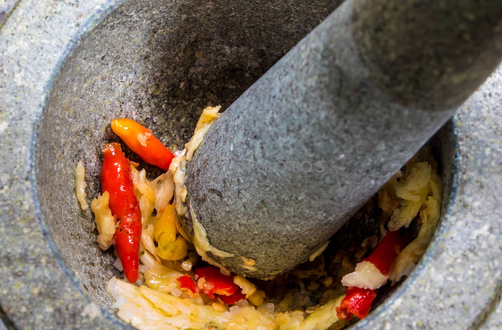 Pepper and garlic are put into a stone mortar to pound