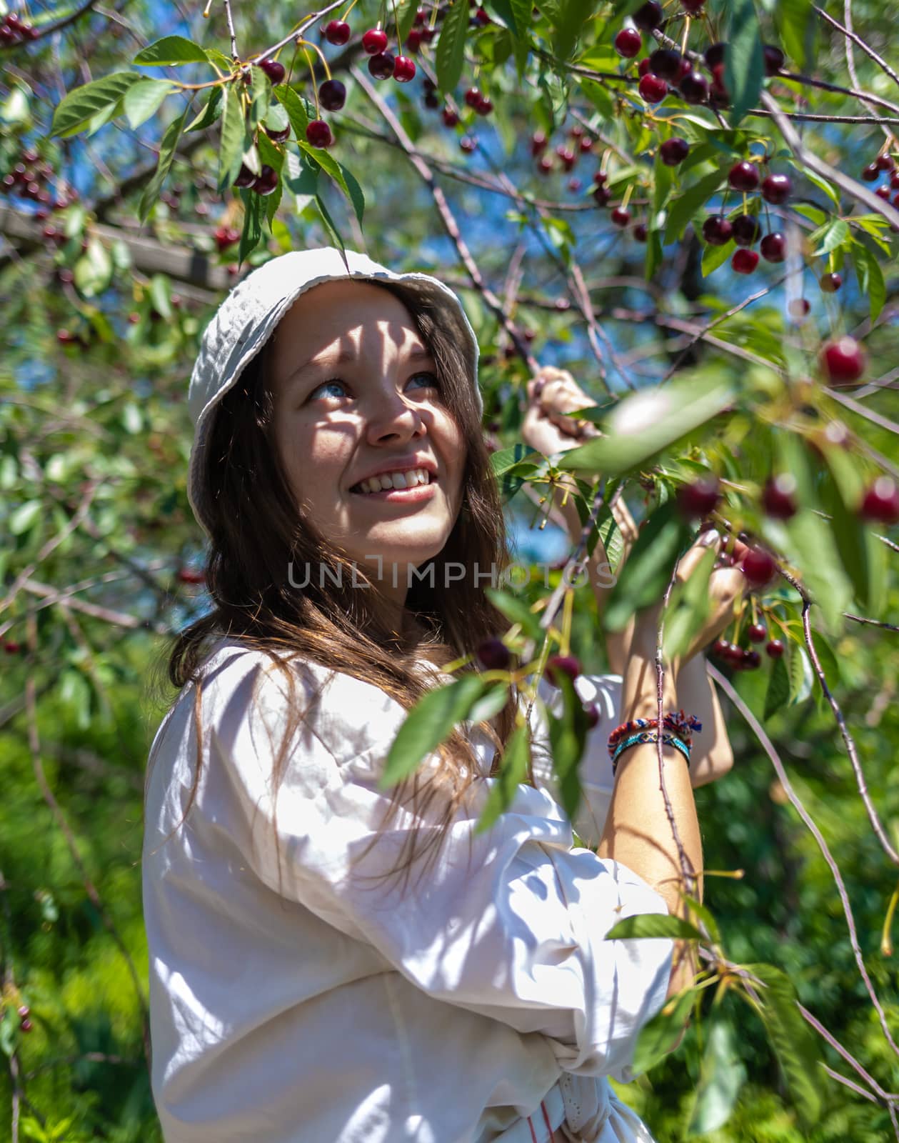 Young, beautiful girl in the bush of viburnum and apple tree