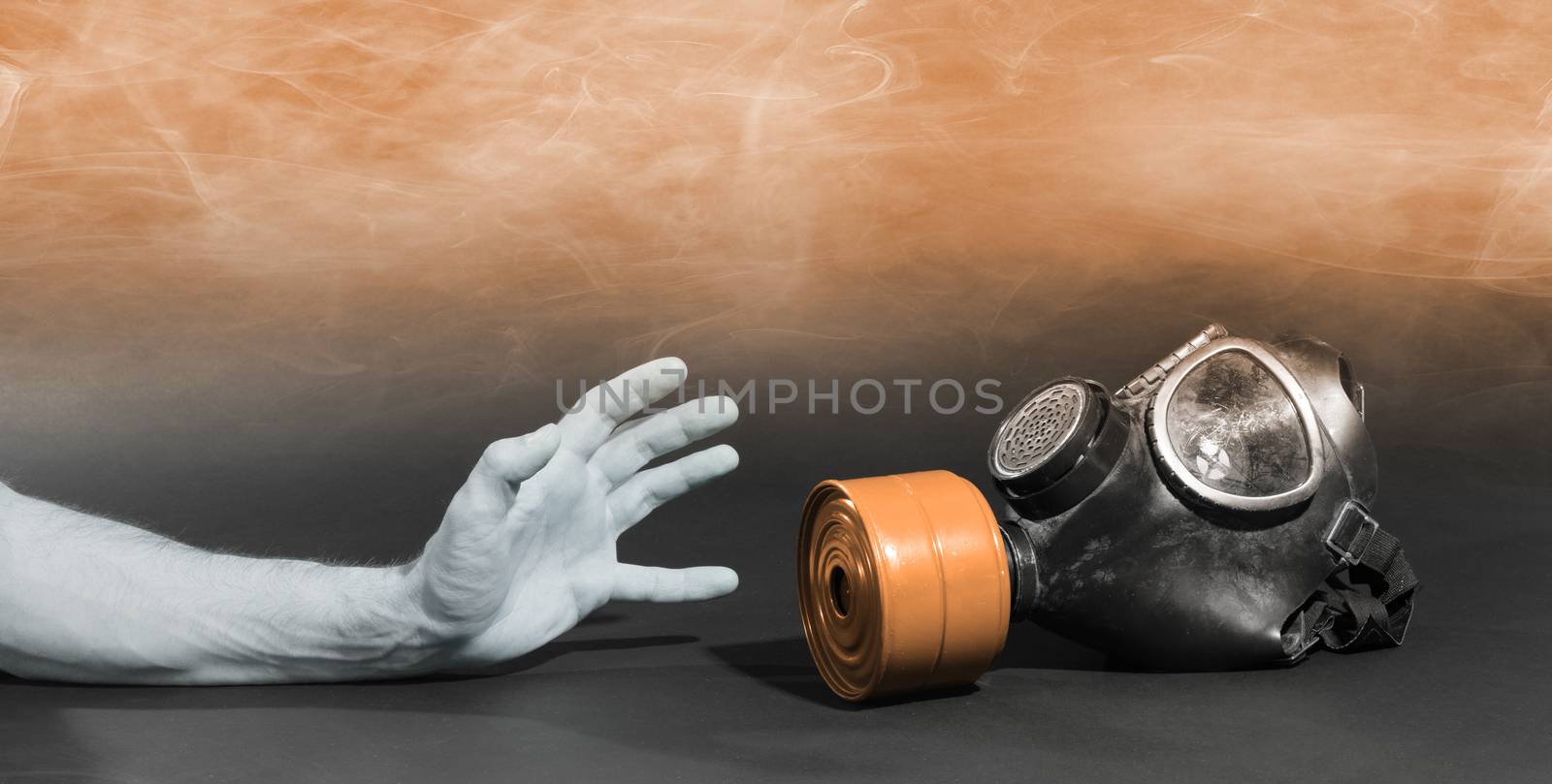 Man in room filled with smoke, trying to reach for vintage gasmask - Isolated on black - Orange smoke