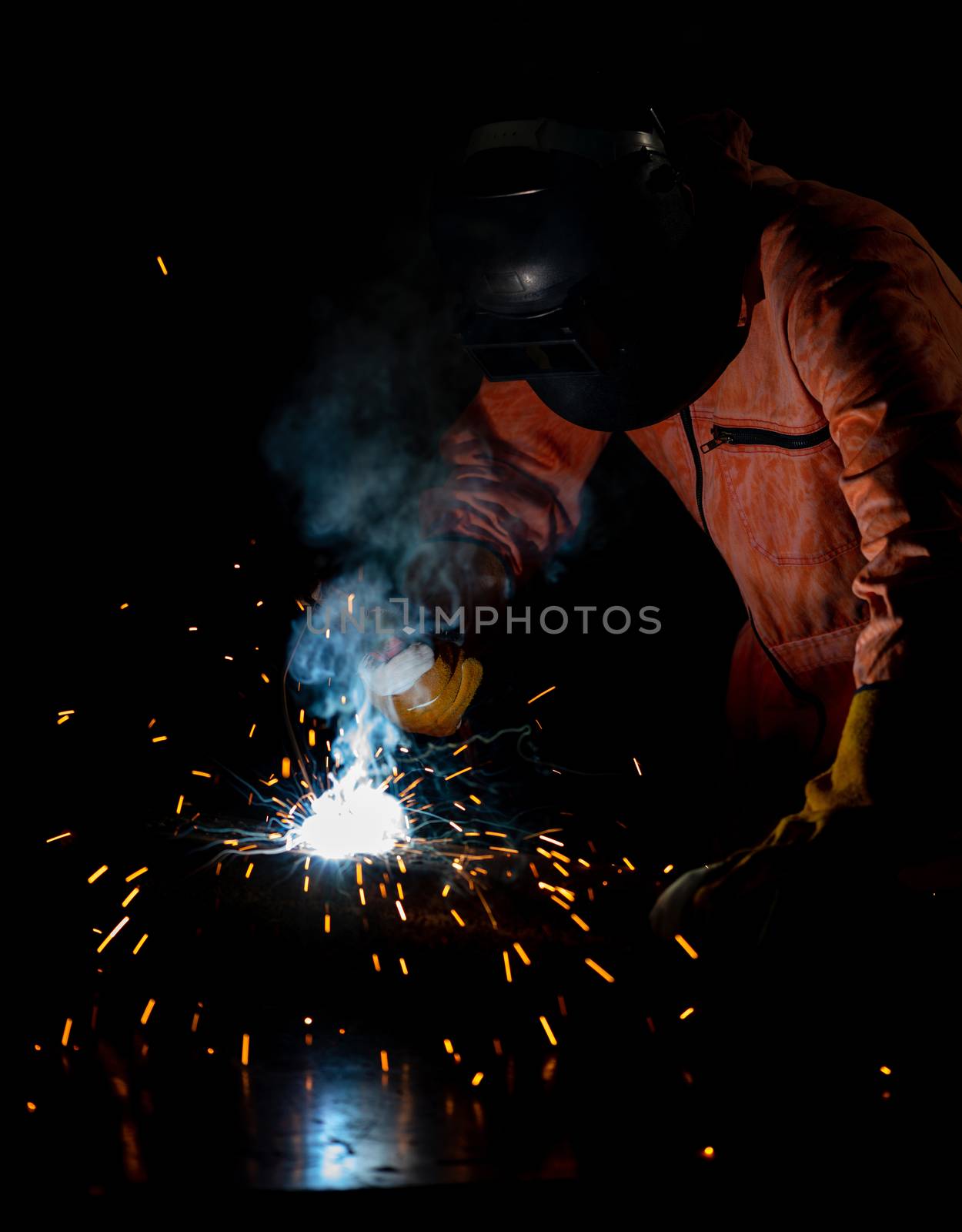 Metal industry workers are welding steel sheets for real estate projects received. Sparkler on black background, close-up. Heavy work in factory.
