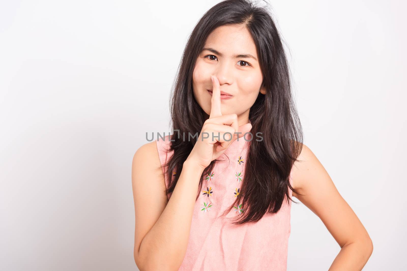 Portrait Asian beautiful young woman standing making hush gesture with fingers and looking to camera, shoot the photo in a studio on a white background, There was copys pace