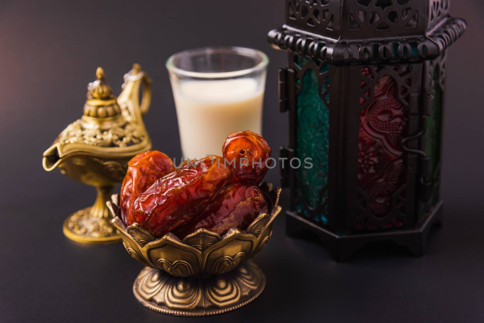 Ramadan Kareem fasting Food Concept, Bronze plate dates, milk, and lantern Aladdin lamp decoration, eid Arabian Muslim religious festival on a black background with copy space for text
