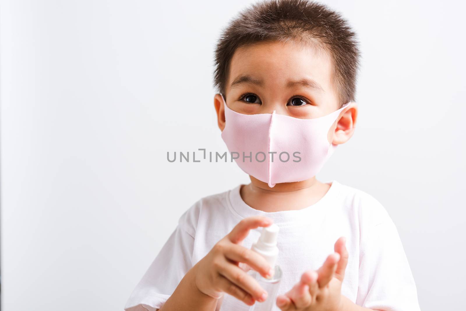 Closeup portrait Asian little child boy holding show bottle pump dispenser sanitizer alcohol spray hand wash cleaning, COVID-19 or coronavirus protection concept, isolated on white background
