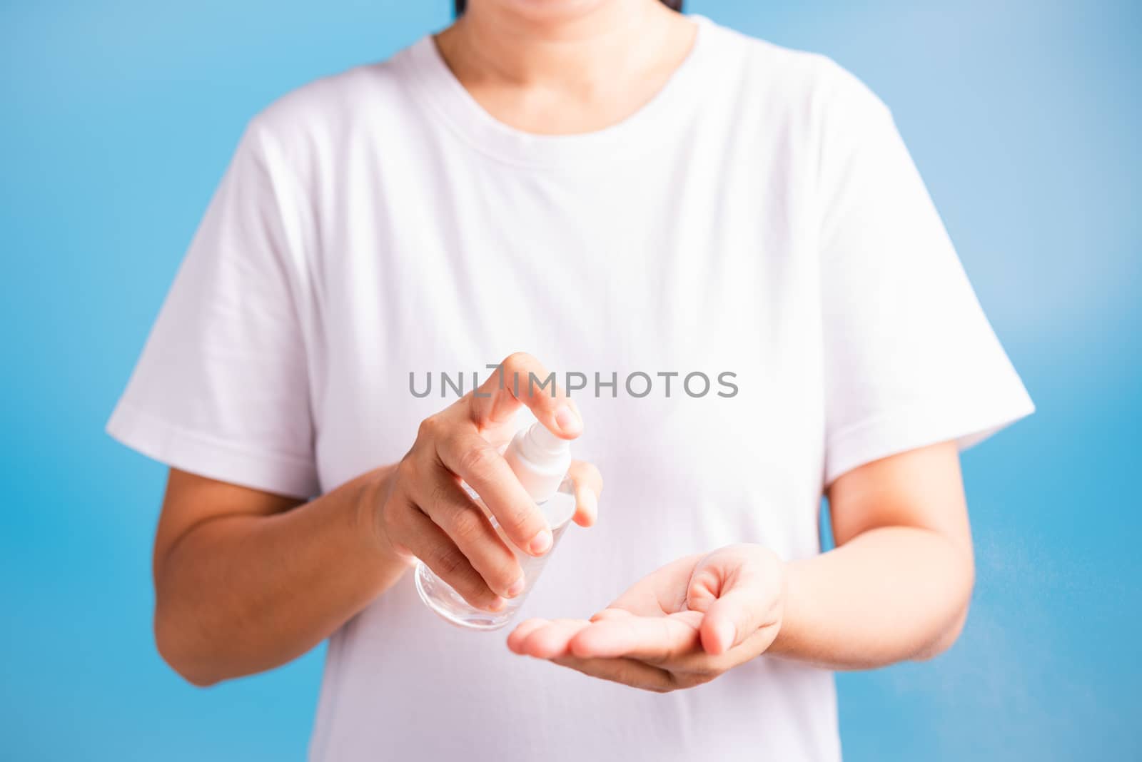 Closeup Hand Asian young woman applying spray pump dispenser sanitizer alcohol on hand wash cleaning, hygiene prevention COVID-19 or coronavirus protection concept, isolated on blue background