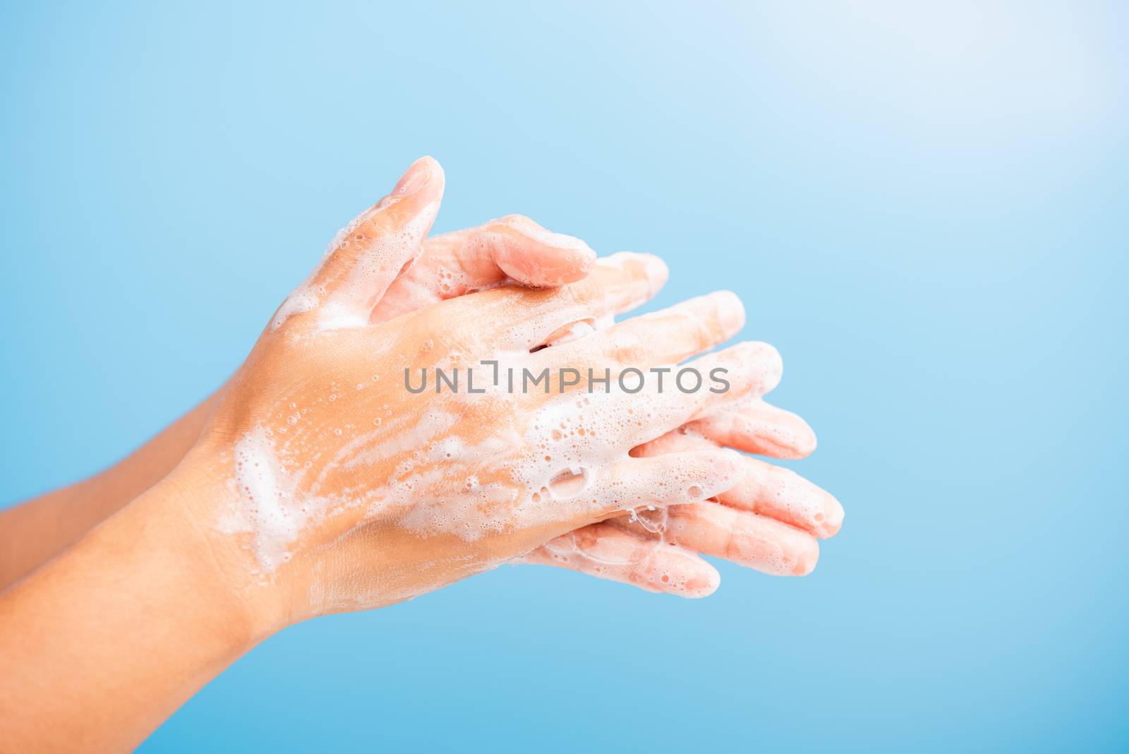Closeup body care Asian young woman washing hands with soap have foam, hygiene prevention COVID-19 or coronavirus protection concept, isolated on blue background
