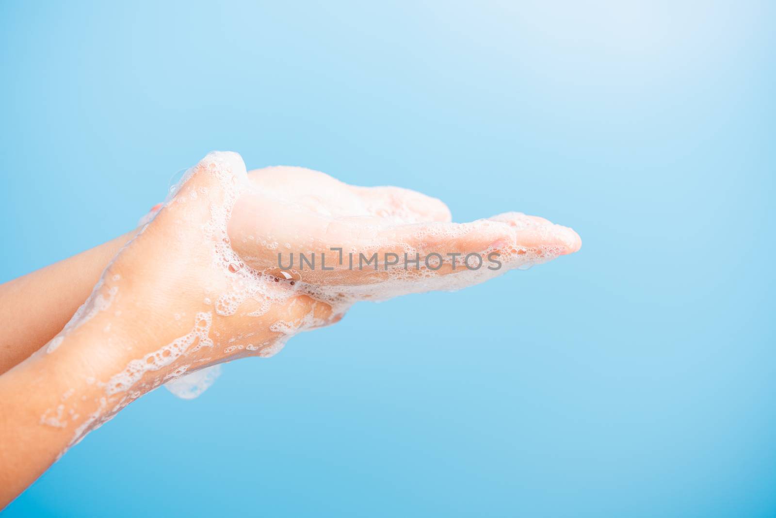 Closeup body care Asian young woman washing hands with soap have foam, hygiene prevention COVID-19 or coronavirus protection concept, isolated on blue background