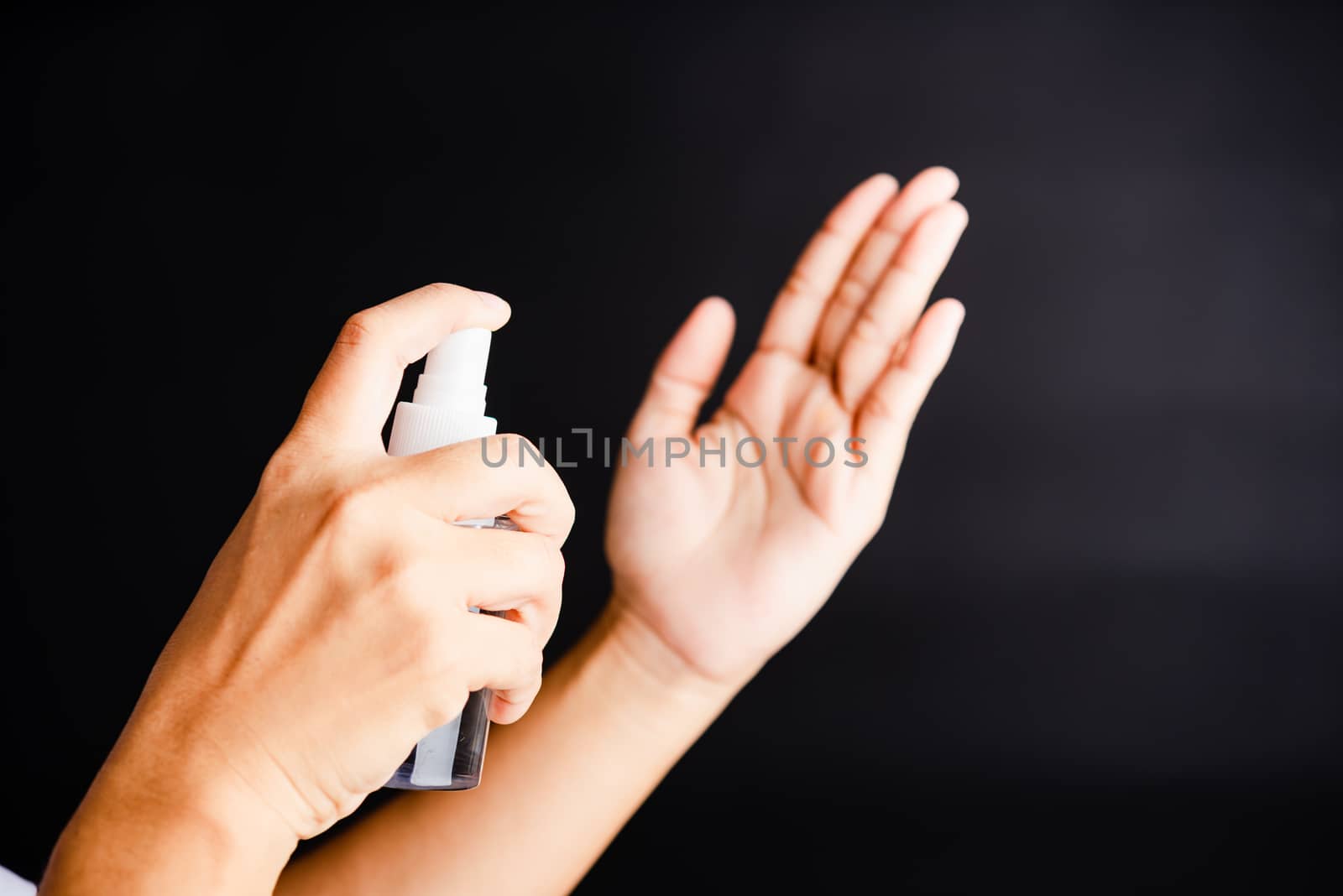 Closeup Hand Asian young woman applying spray pump dispenser sanitizer alcohol on hand wash cleaning, hygiene prevention COVID-19 or coronavirus protection concept, isolated on black background