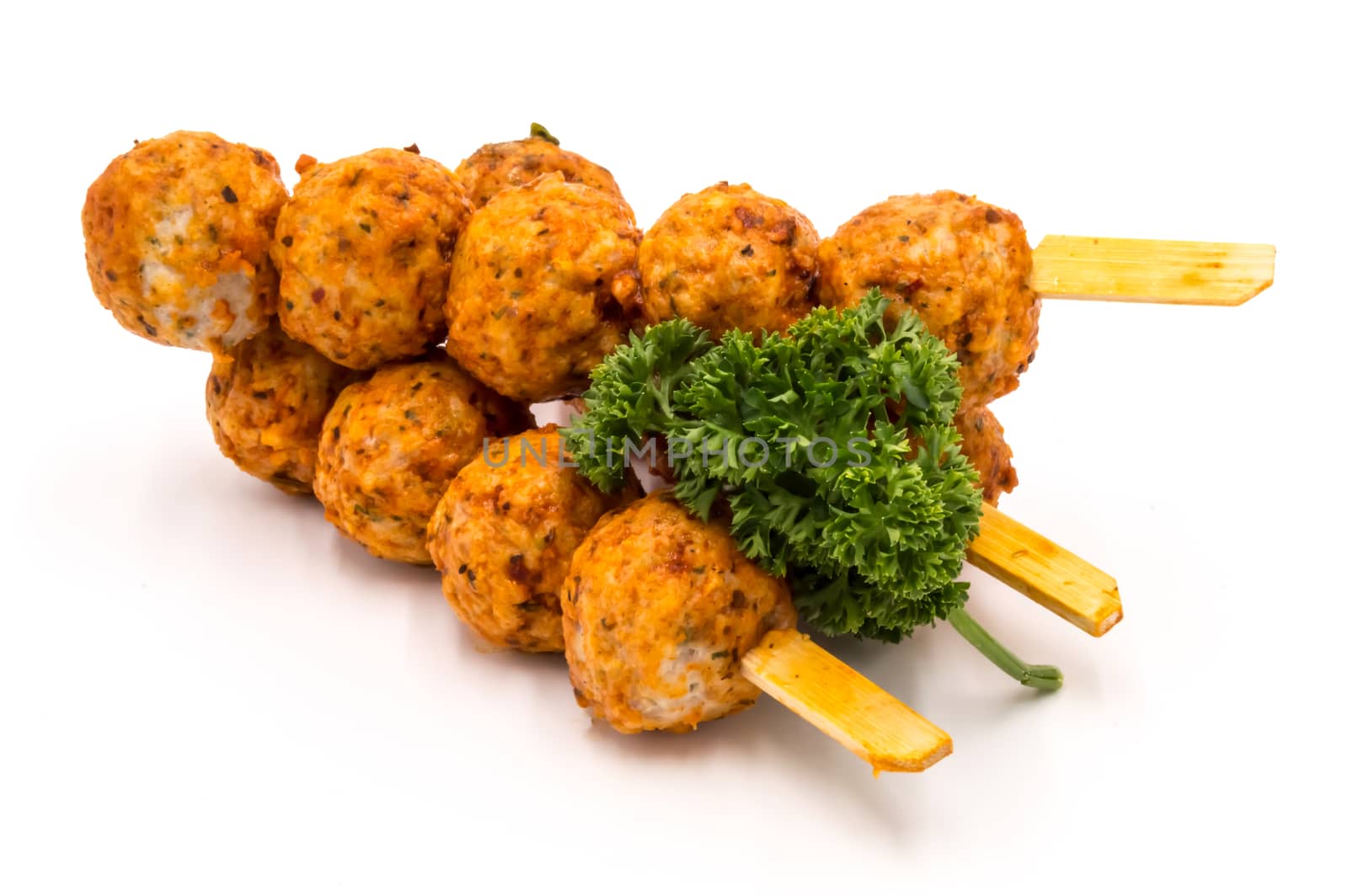 Marinated meatballs skewers on a wooden pick and a white background.