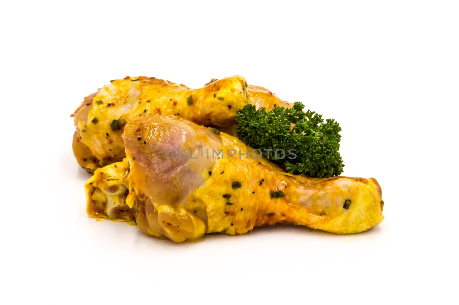 Chicken drumsticks marinate with parsley on a white background