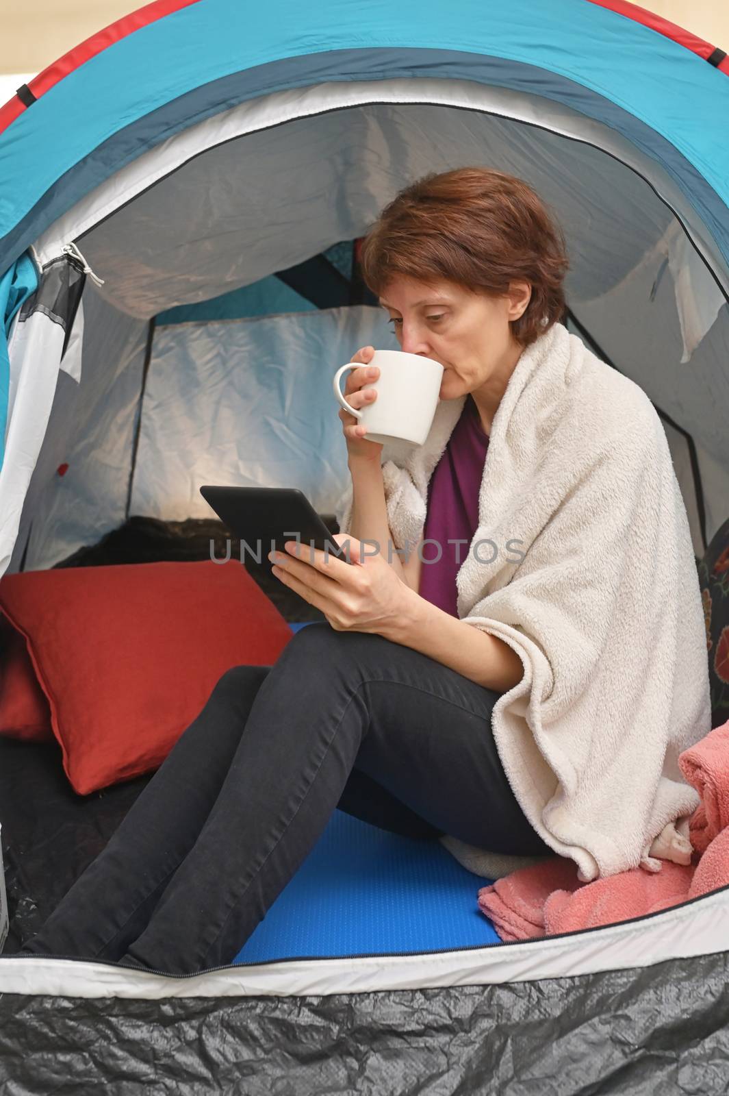 Quarantine At Home. Woman sit inside a tent enjoying a cup of tea