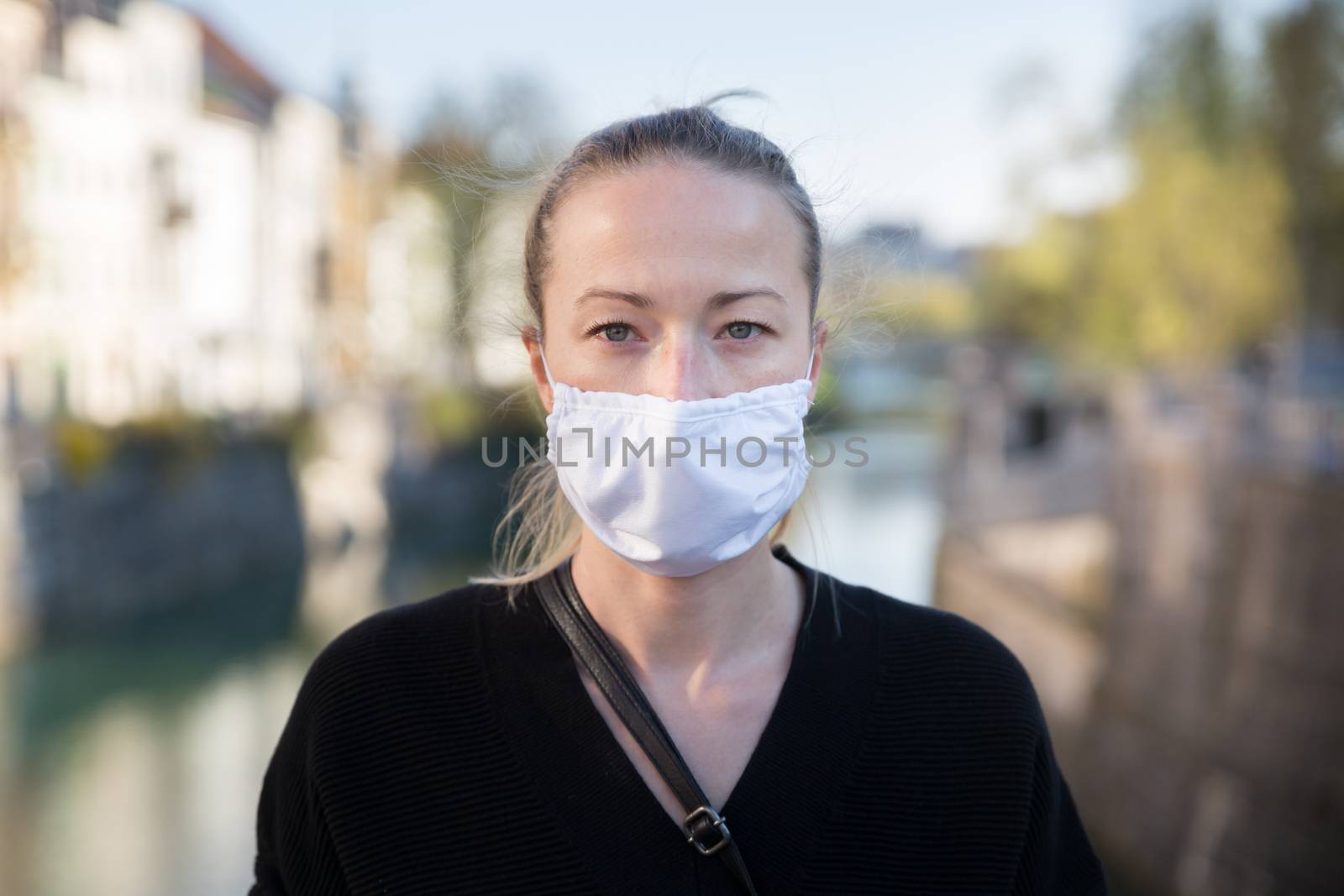 COVID-19 pandemic coronavirus. Young girl in city street wearing face mask protective for spreading of coronavirus disease 2020. Close up of young woman with medical mask on face against SARS-CoV-2.