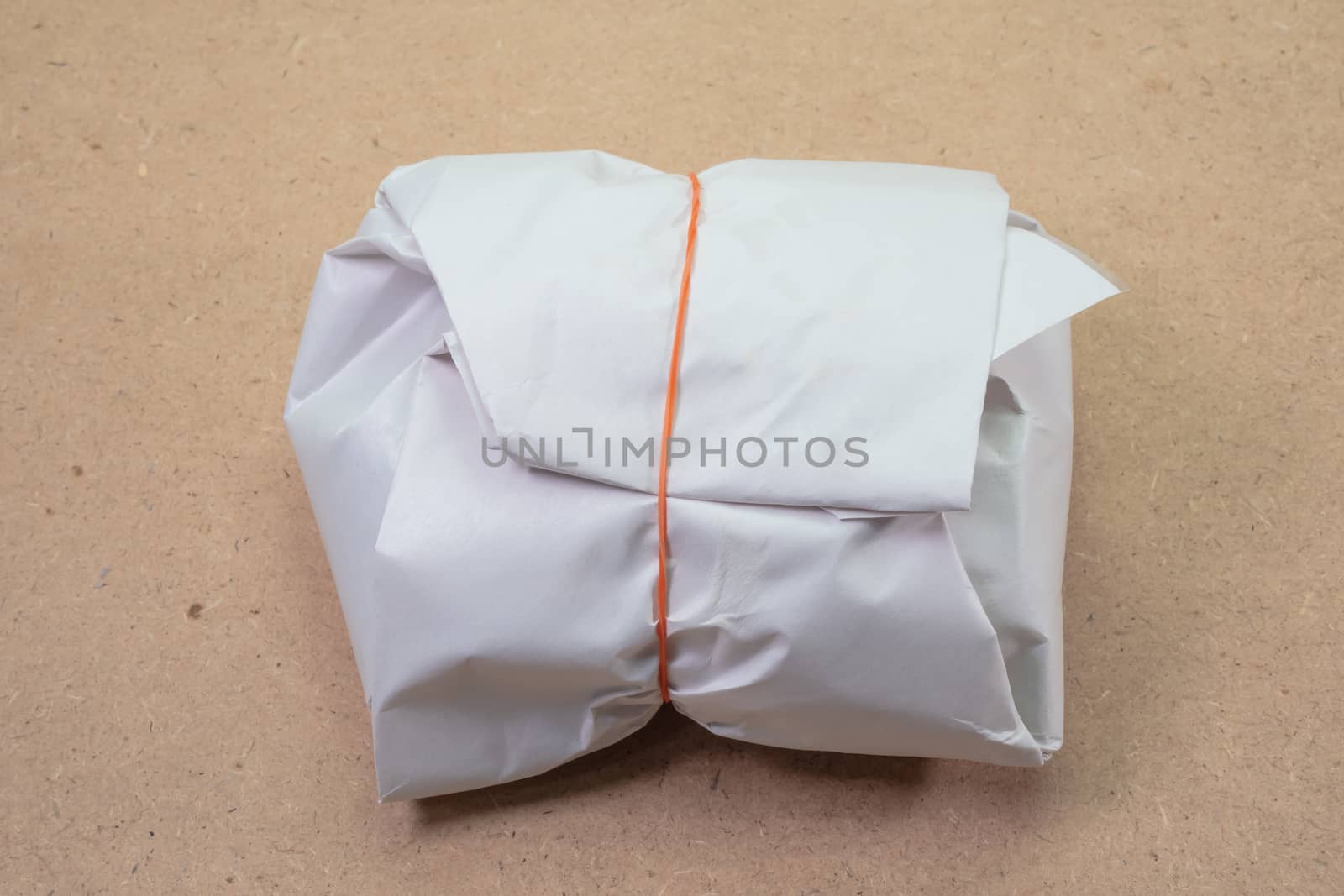 The close up of Thai traditional paper sheet packageing of chicken rice food on wooden board.