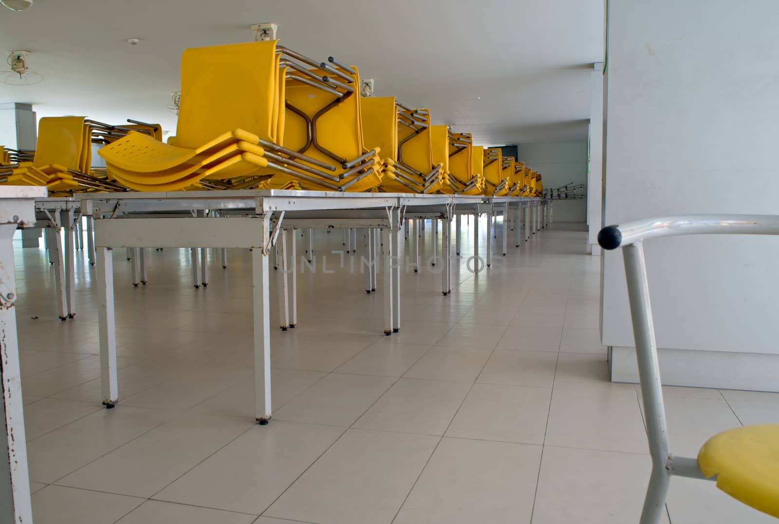 Many yellow plastic chairs stacked on the table