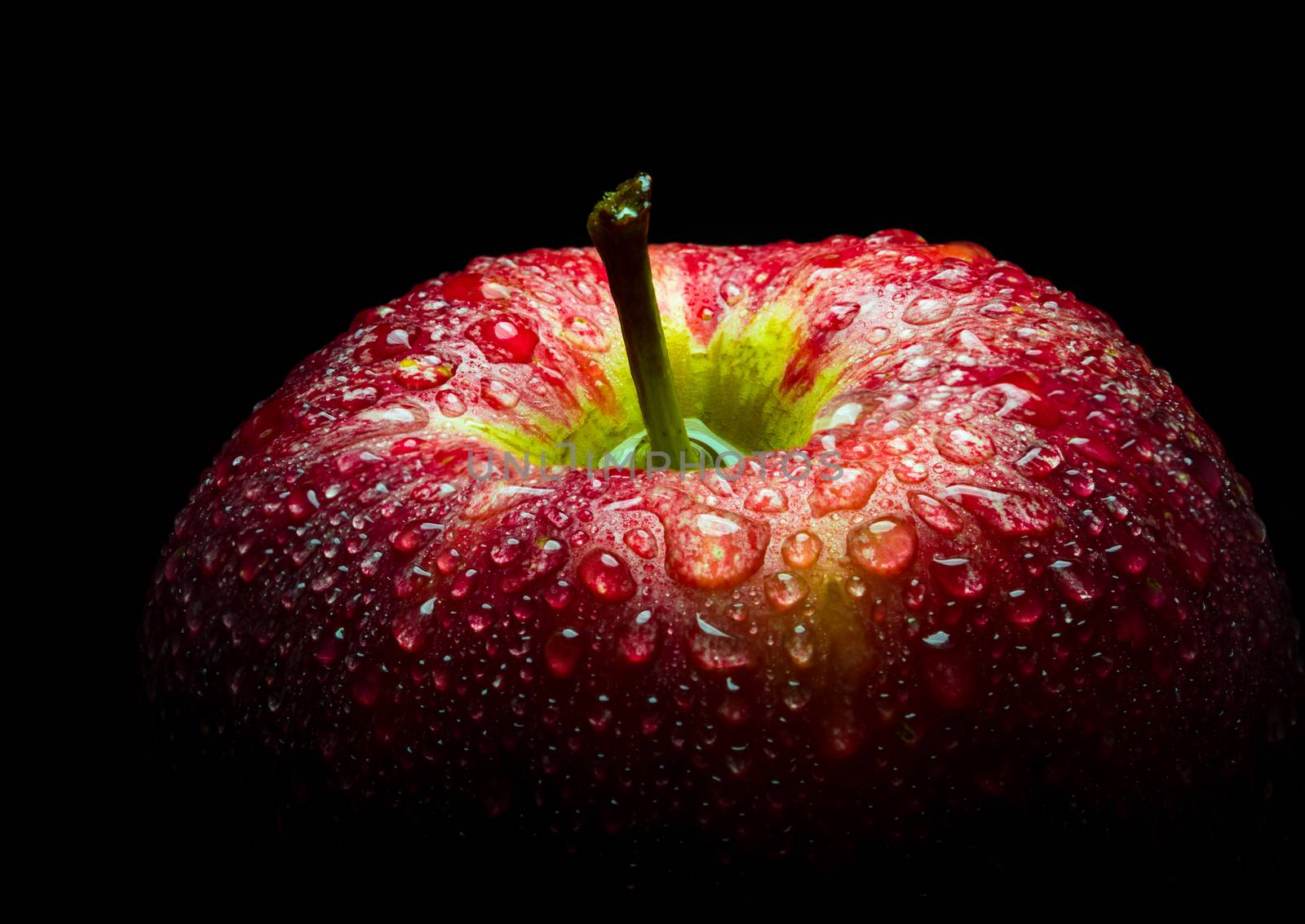 Water droplet on glossy surface of red apple on black background by Satakorn